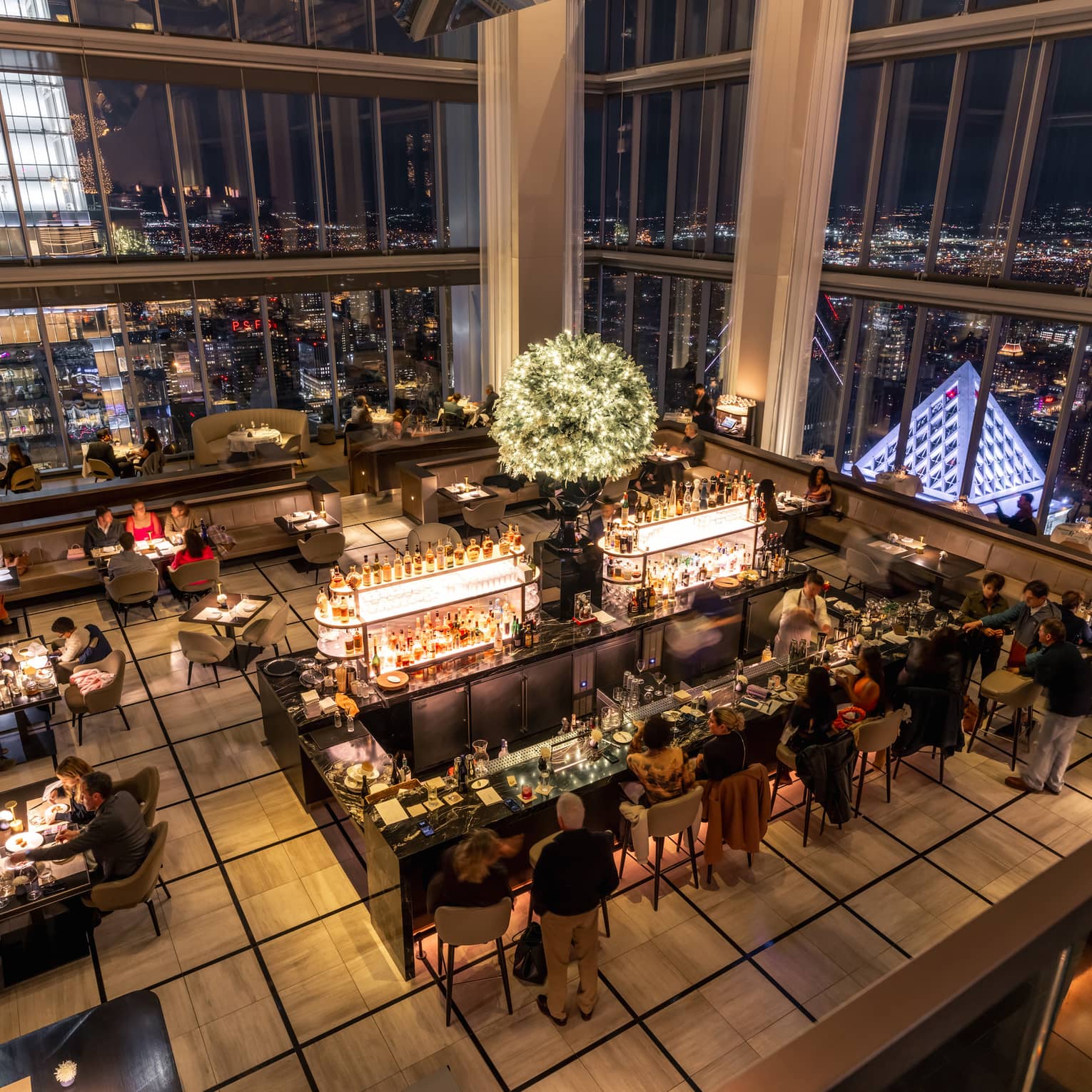 Aerial view of a dining room with floor-to-ceiling windows and a view of the city.
