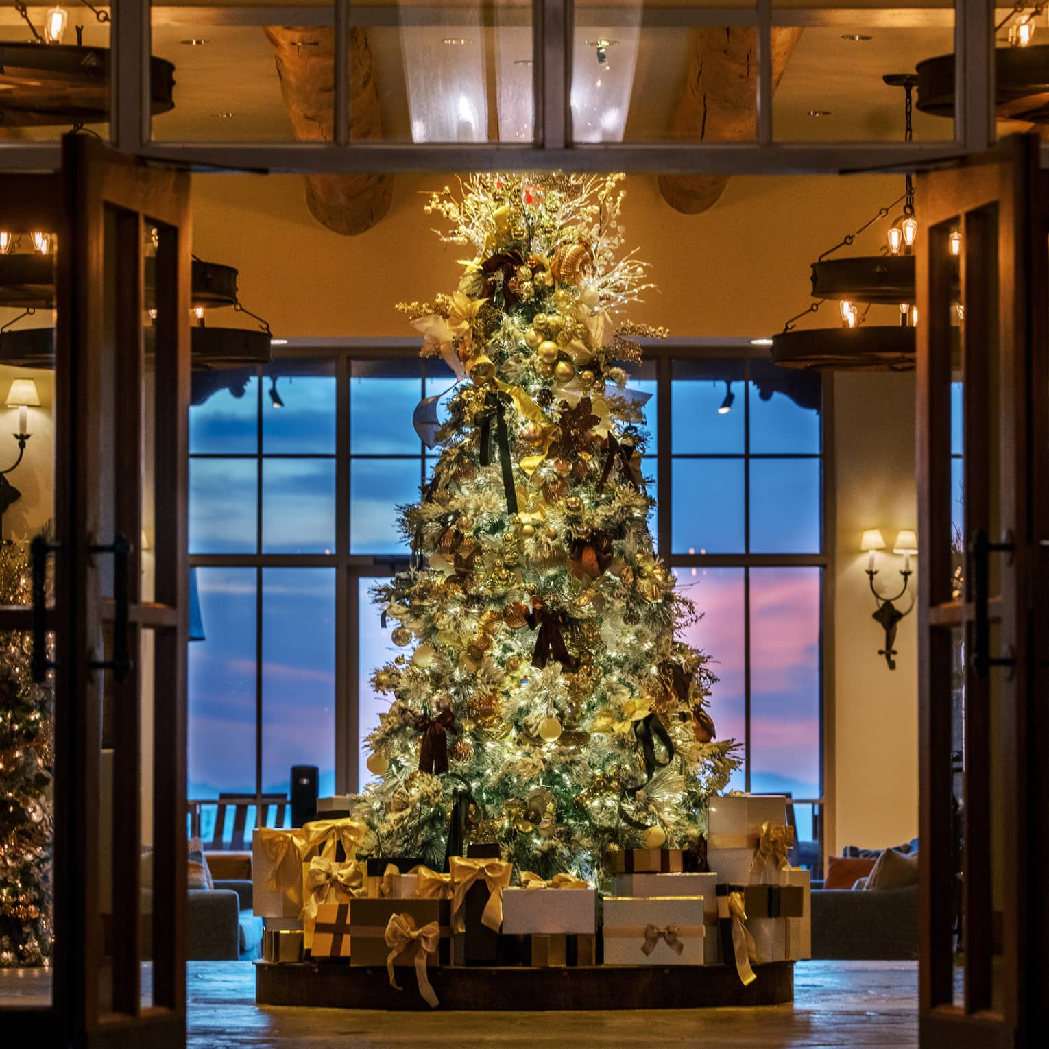 A tree decorated with lights and ornaments and surrounded by presents