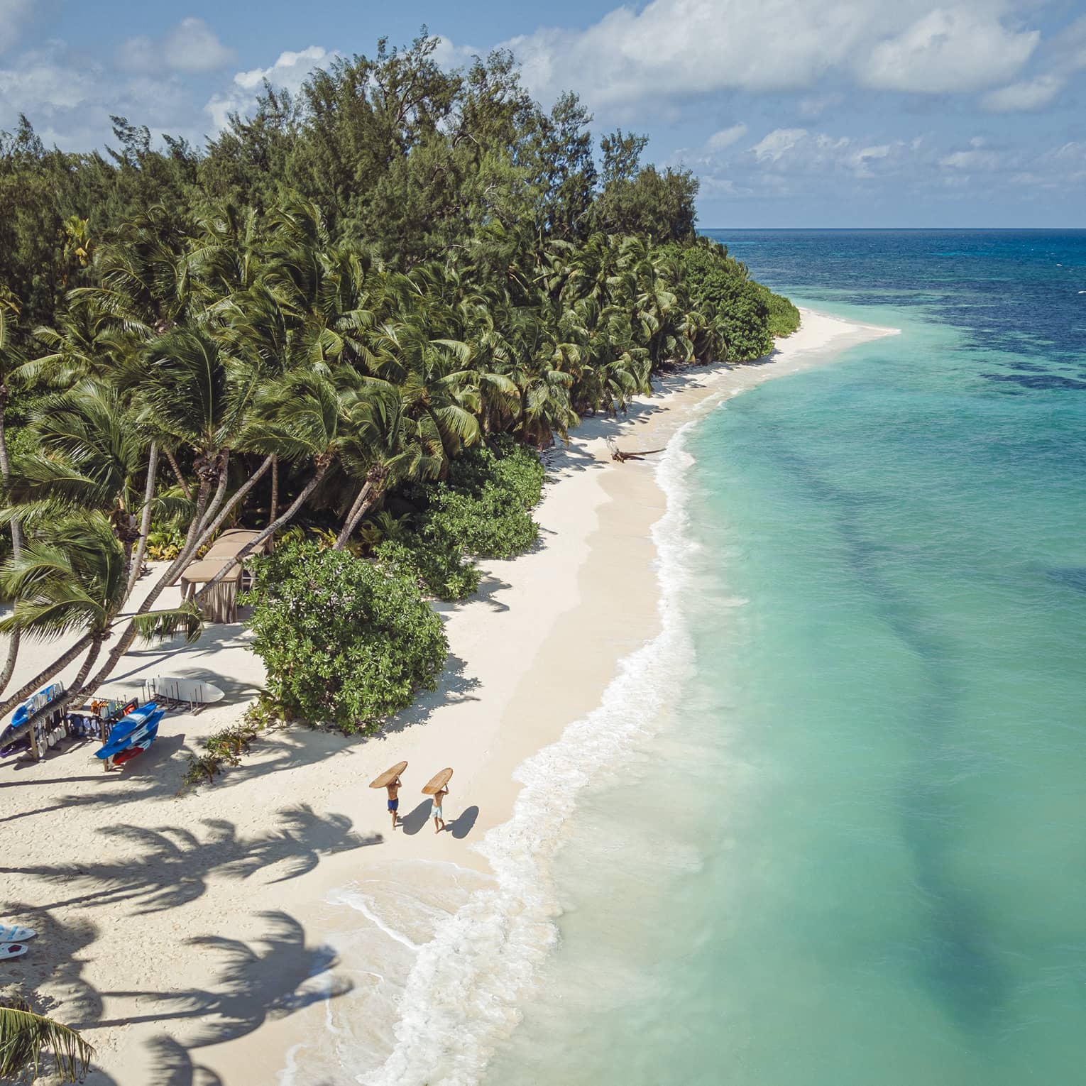 Tropical beach with turquoise water, and narrow white-sand beach in between sea and trees