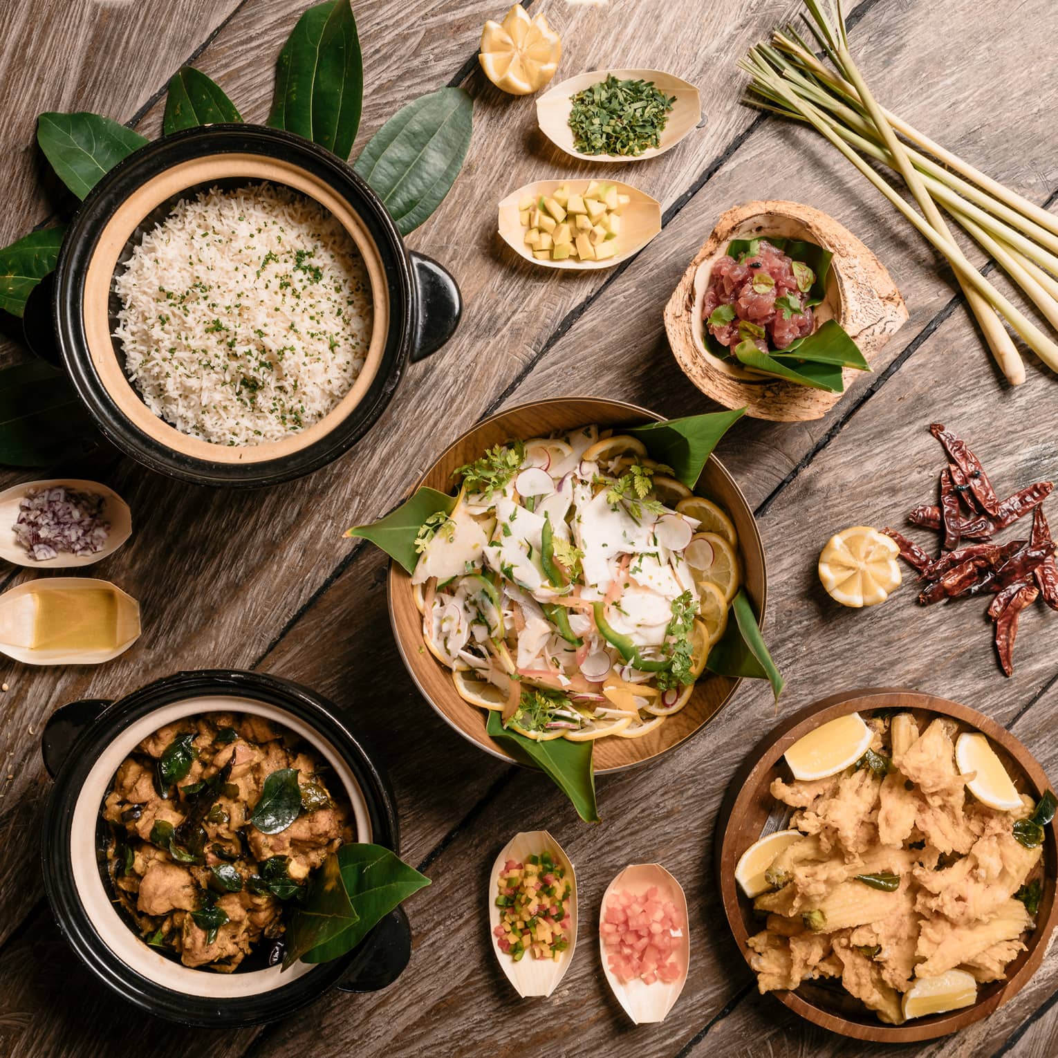 Aerial view of rustic wood table with bowls of gourmet rice, salads and entrees