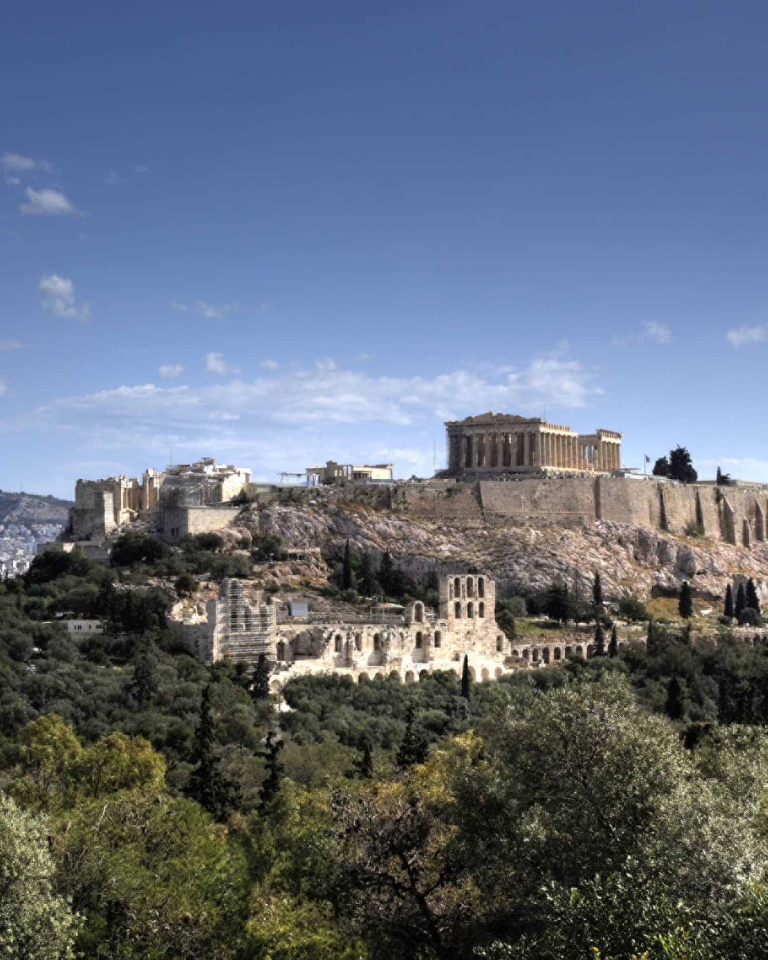 Ancient ruins of Acropolis on mountain surrounded by greenery 