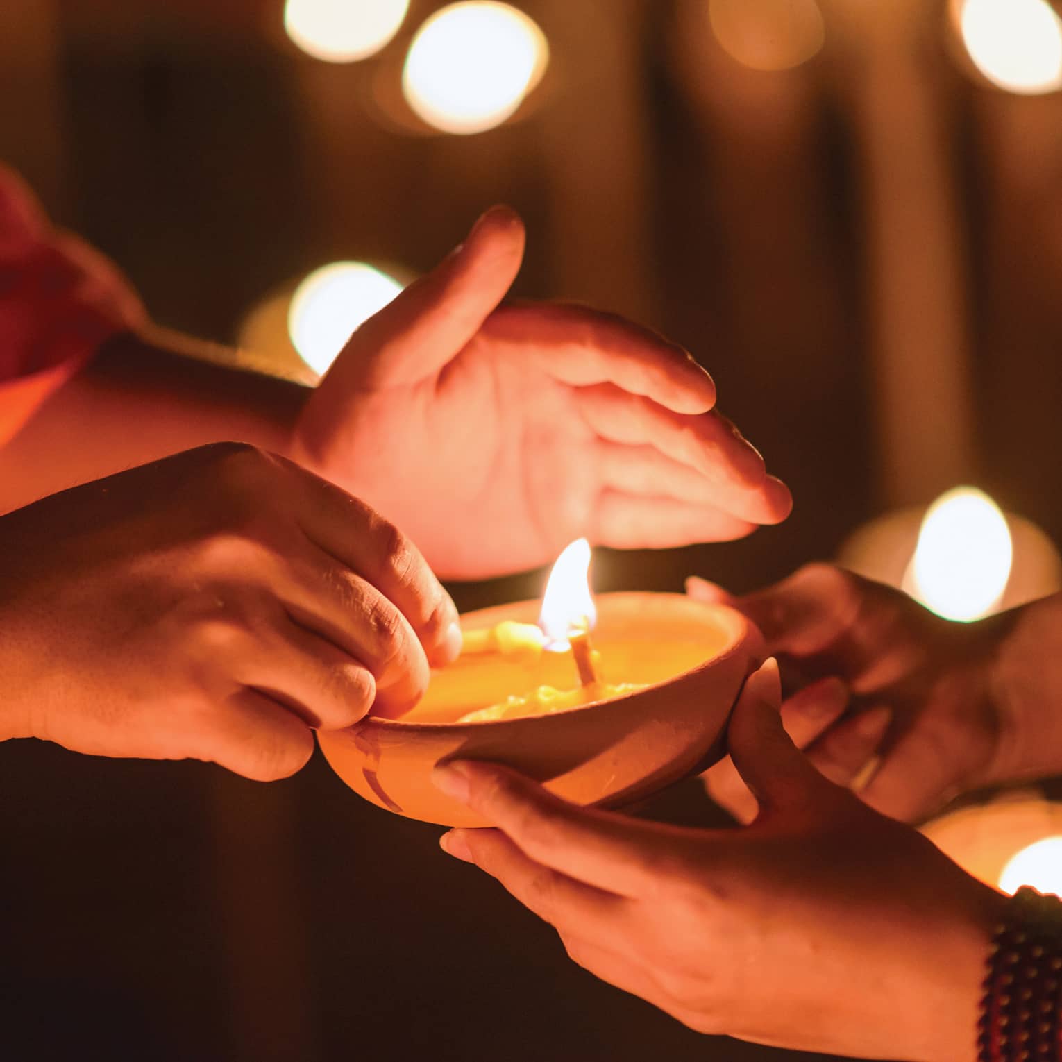 Buddhist monk hands holding candle cup in dark