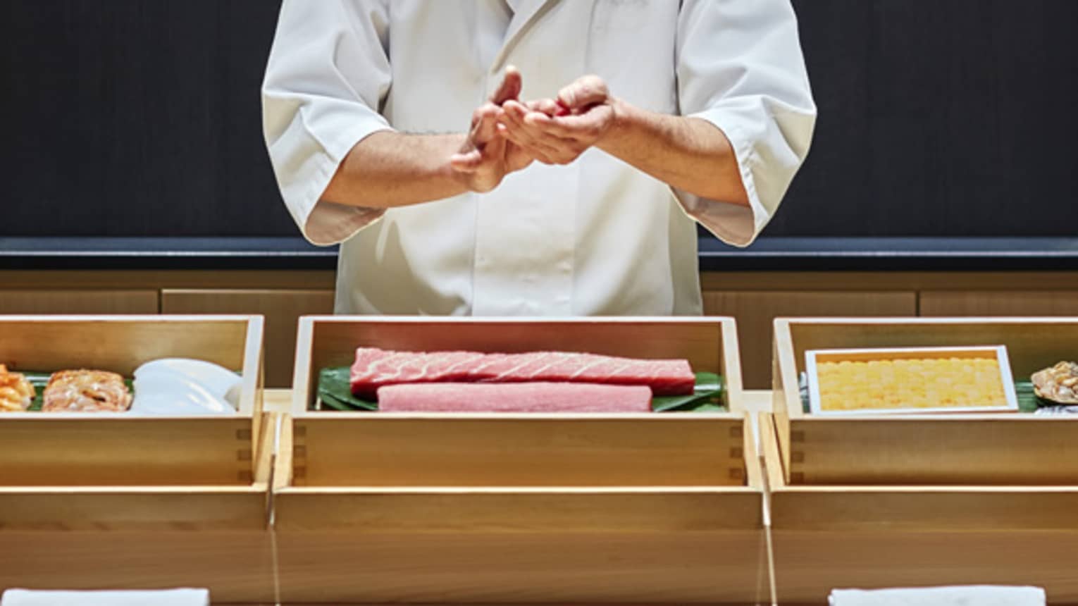 Sushi chef prepares fish behind bamboo display, Sushi wakon bar