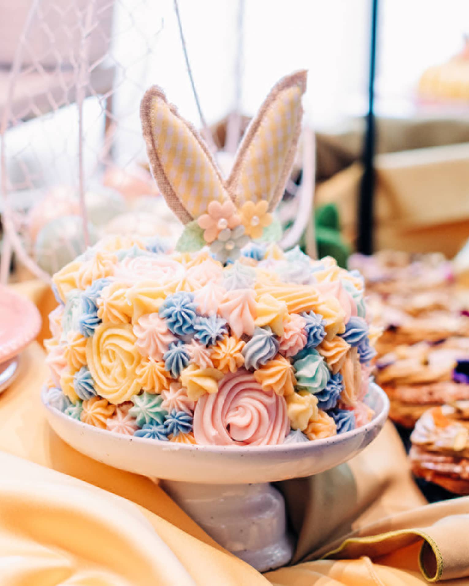 A cake with yellow, blue and pink icing and bouquets of flowers