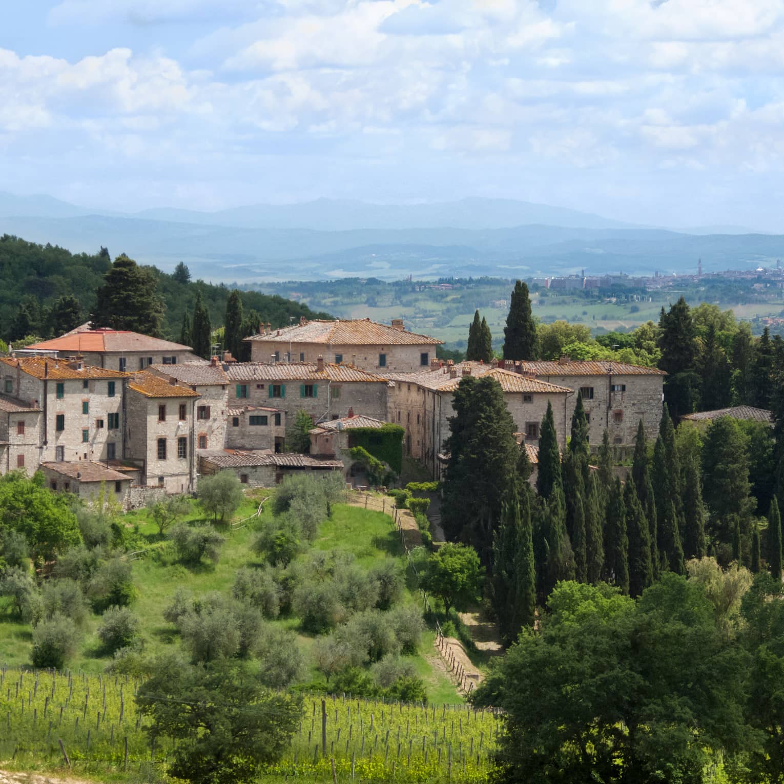 Tuscan countryside with historic stone building against rolling green hills