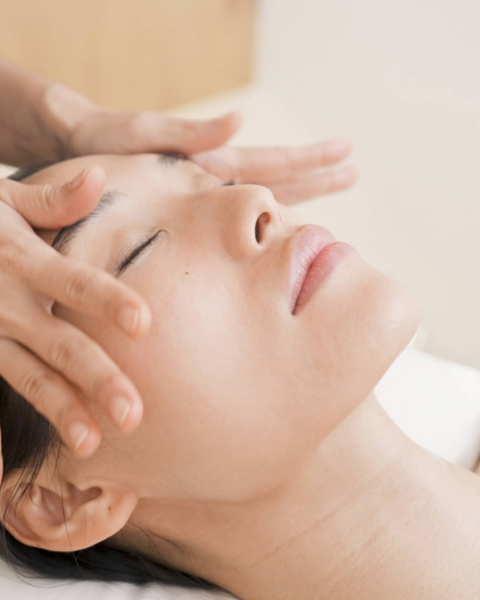 Person with eyes closed receiving head massage