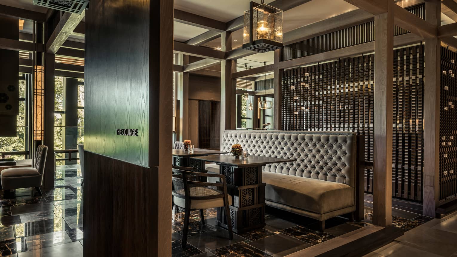 The Lounge plush velvet booth between dark wood walls under thick glass chandelier