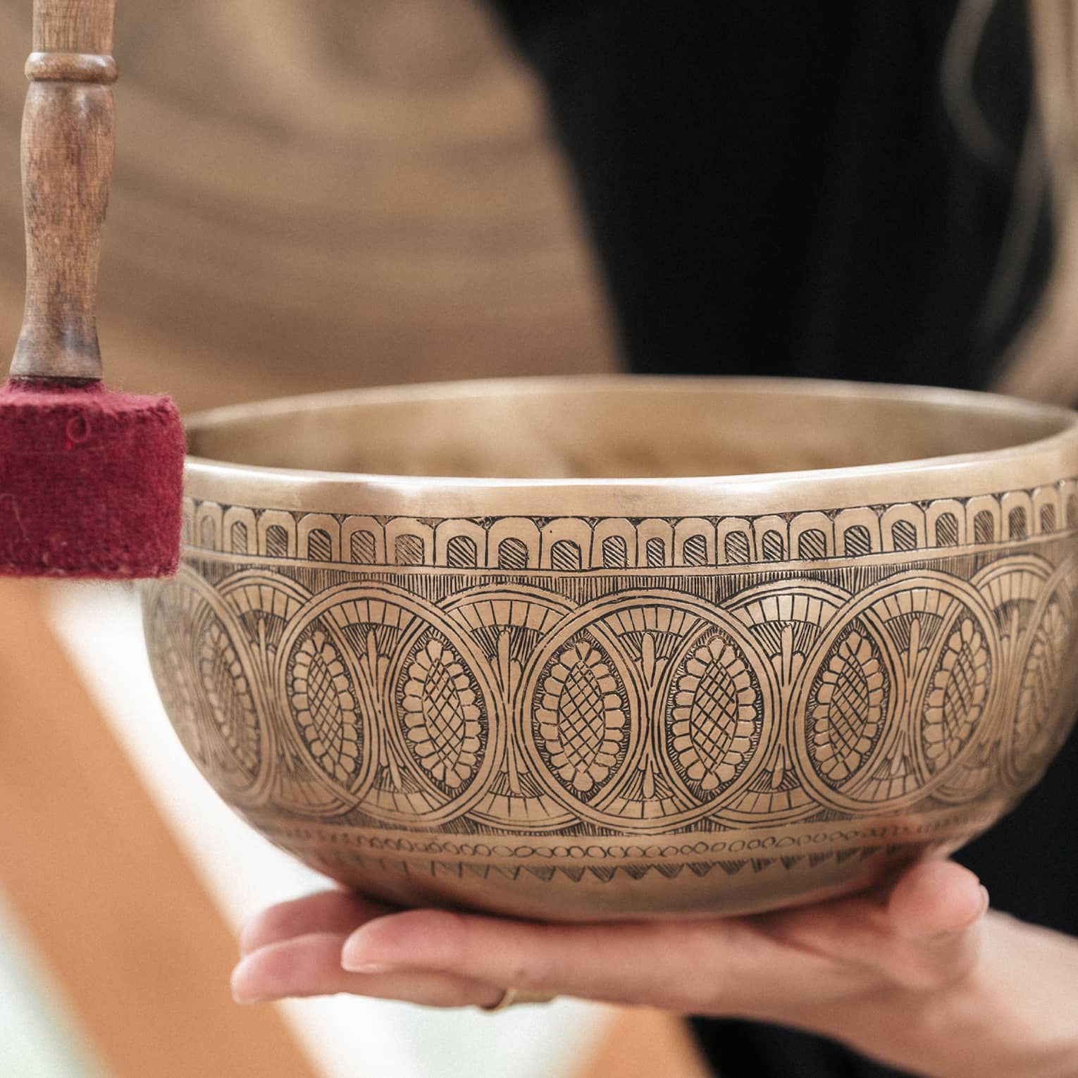 Person holding a gold engraved sound bath healing bowl