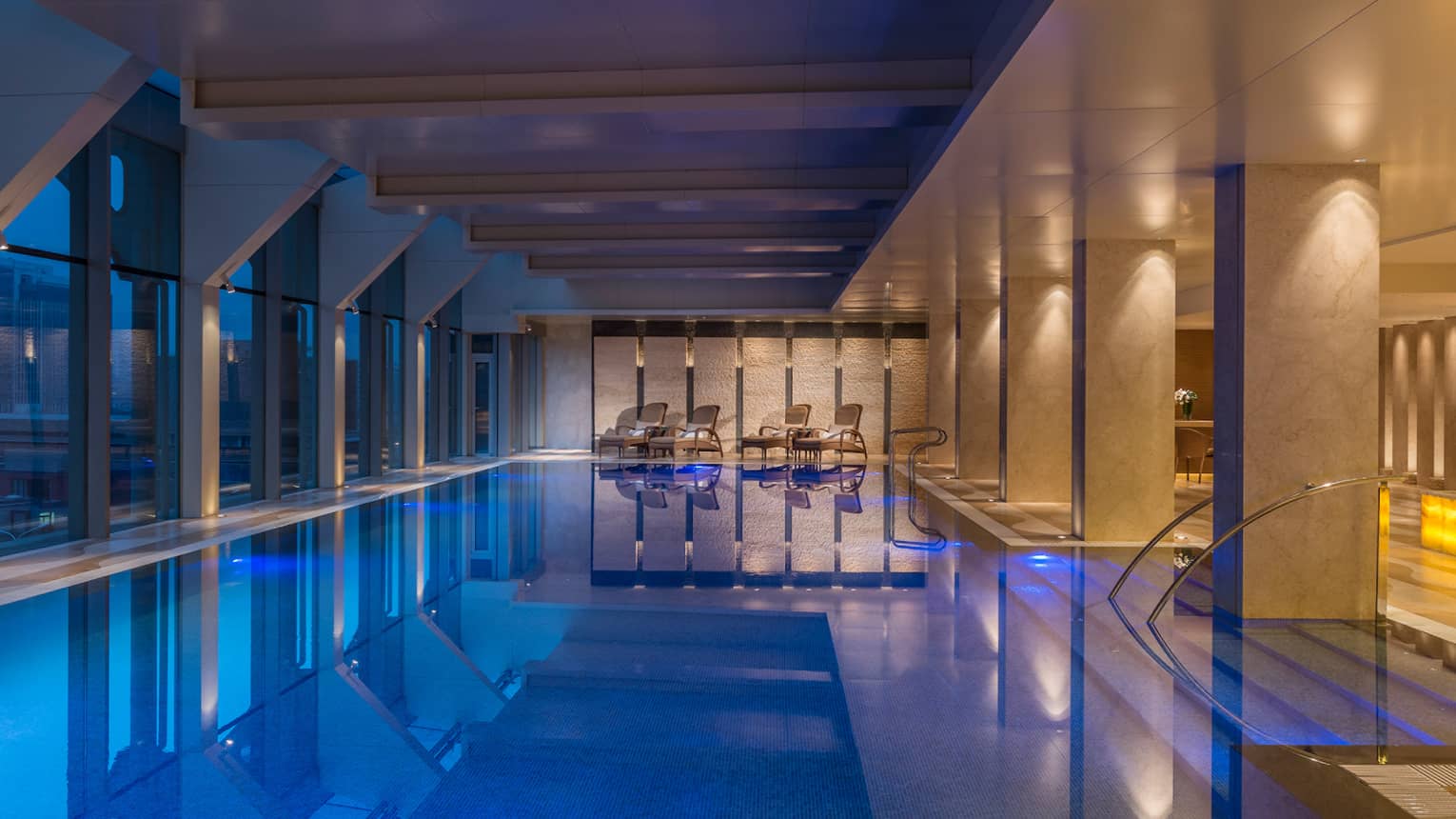 A 20-metre indoor pool surrounded by soft lighting as the sky darkens outside. 
