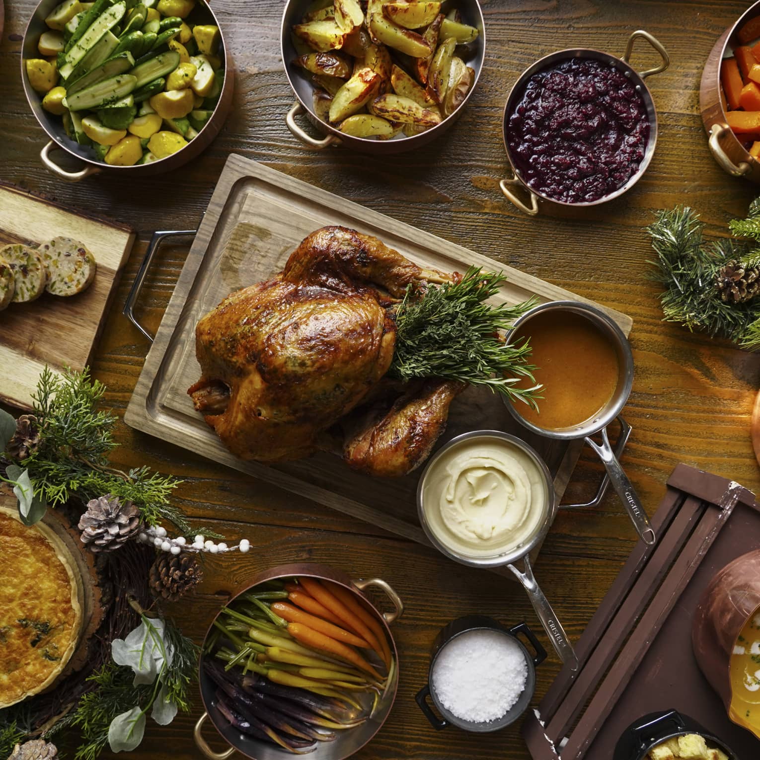 A full festive feast with a Turkey in the centre, and several copper pots of stewed vegetables surrounding