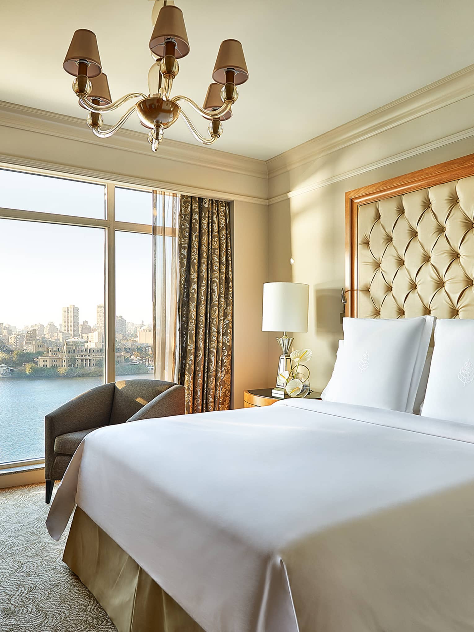 Diplomatic Suite bed with large tufted headboard by floor-to-ceiling window
