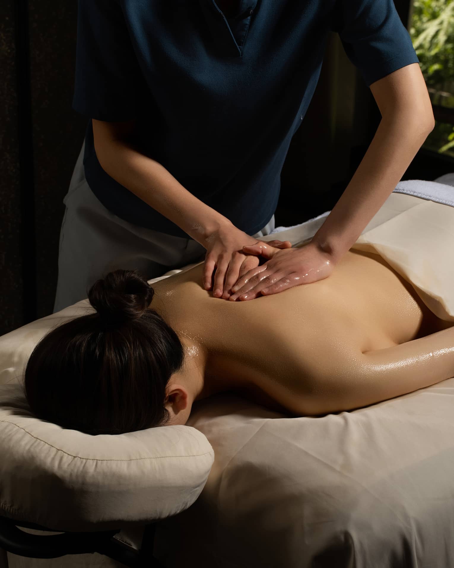Person lying face down and covered in a beige sheet getting a massage