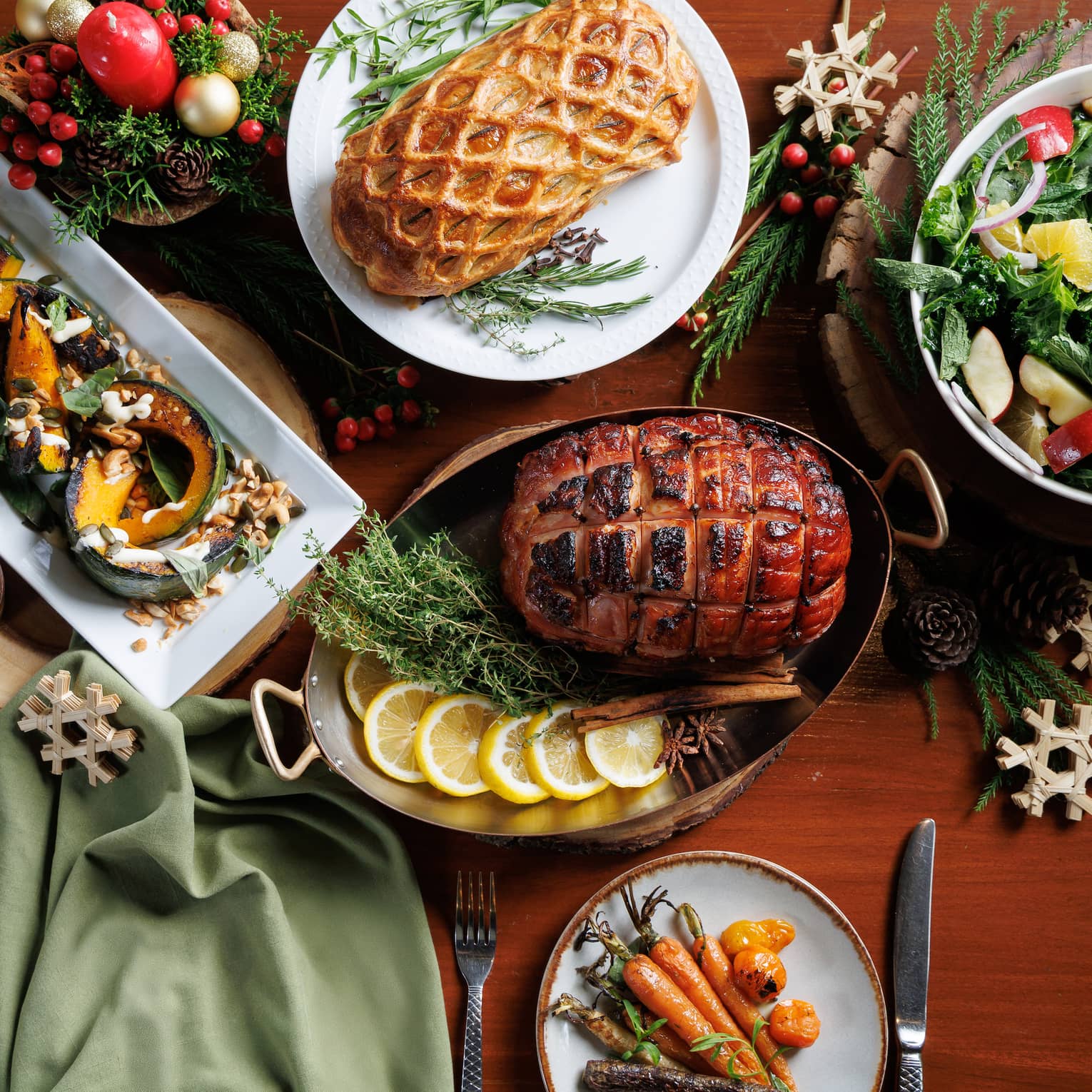 Baked ham, bowl of salad, sliced melons and more fill a table set for a Christmas meal