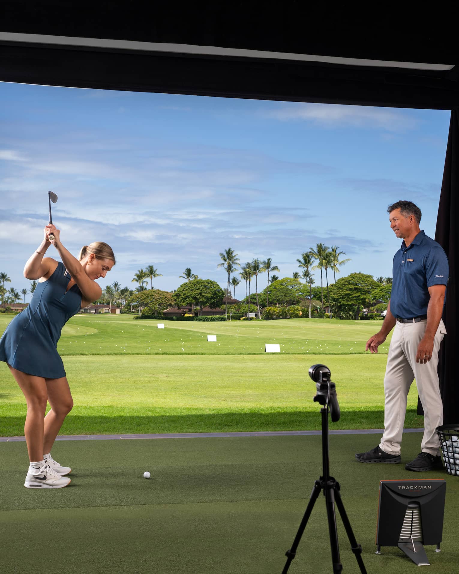 A woman practices her golf swing in an indoor simulator setting.