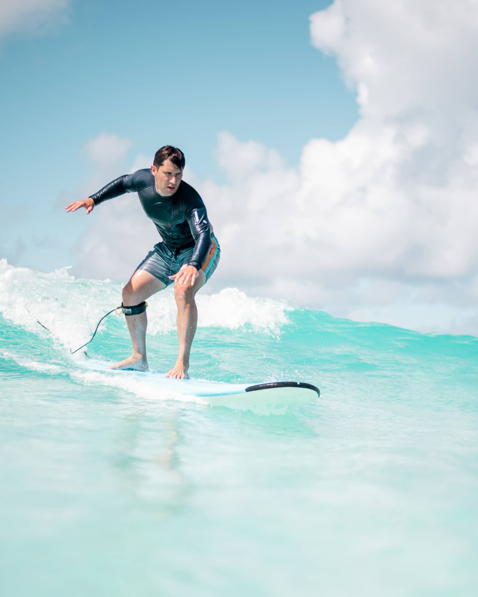 Man balances on surf board over wave