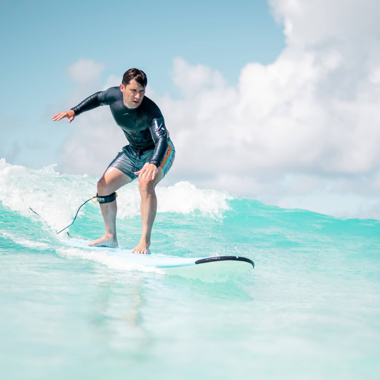 Man balances on surf board over wave