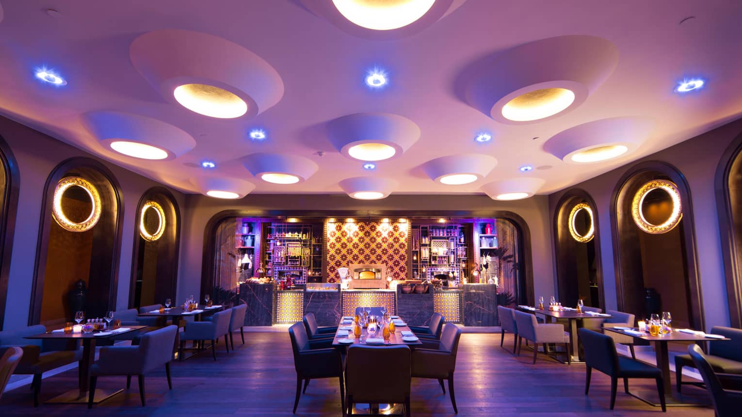 Candle-lit tables, chairs in Quattro dining room with large modern pot lights in white ceiling