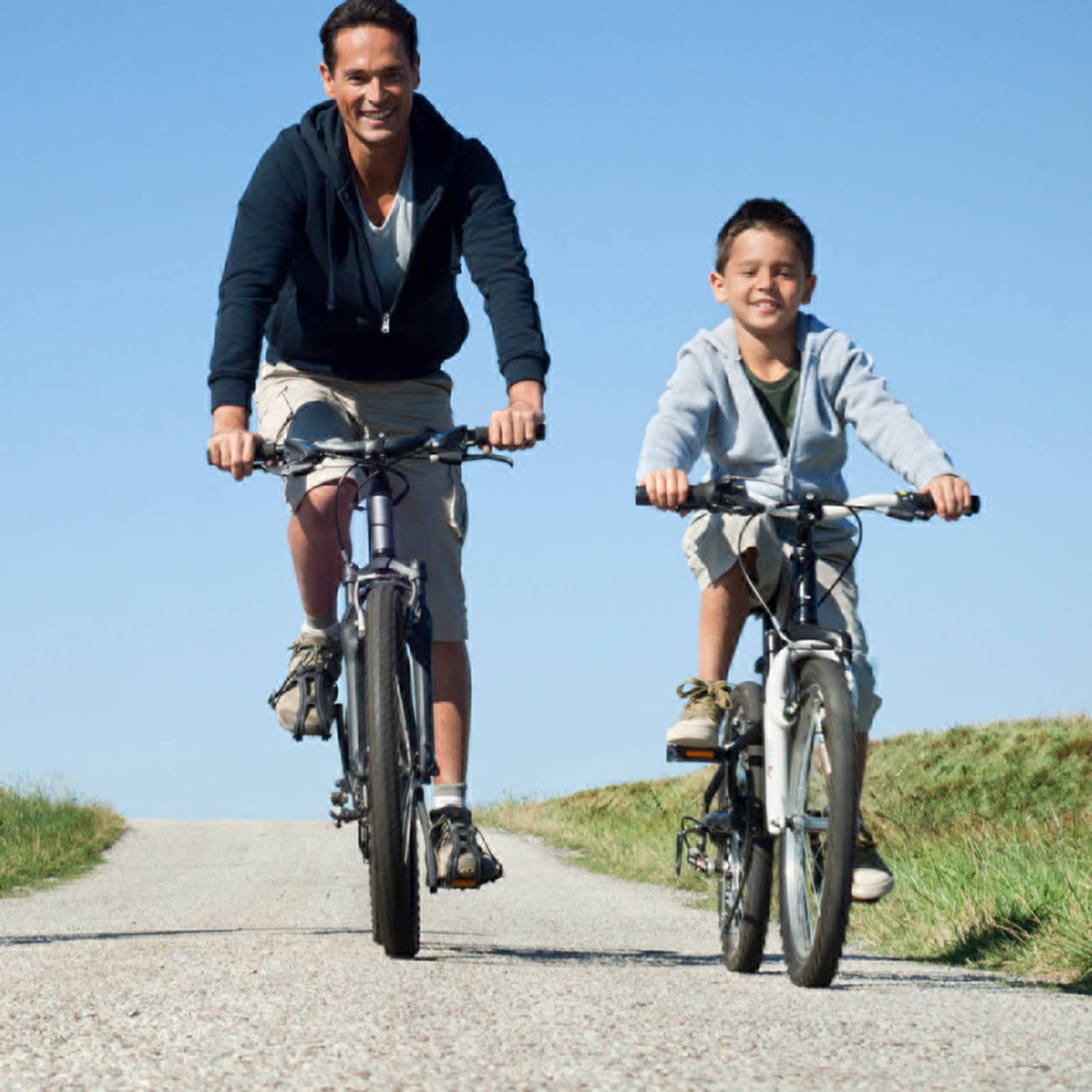 Family of three cycling on countryside pebble path