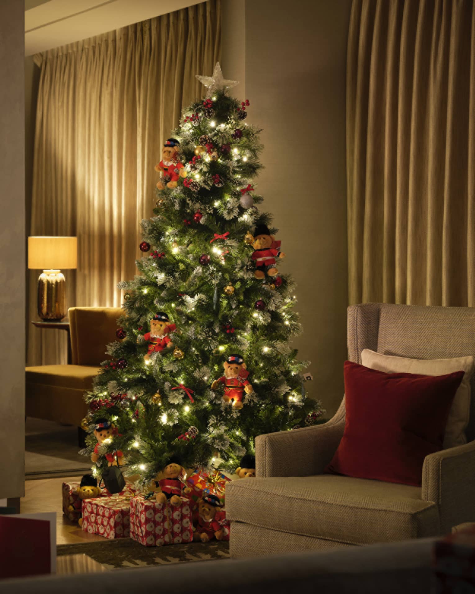 Christmas tree lit up in a dimly lit living room with fireplace
