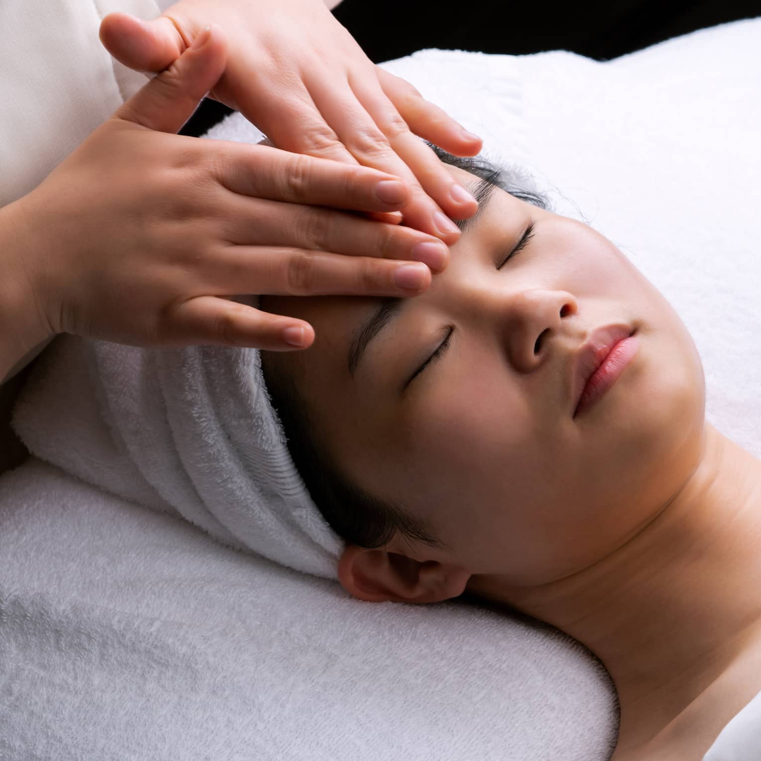 Spa staff places hands on woman's forehead during Anti-Oxidant Facial