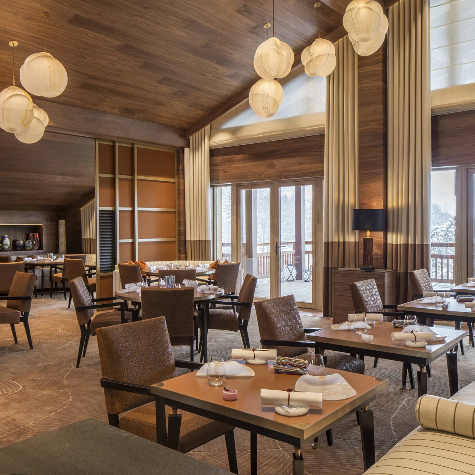 Tables, brown leather chairs, striped banquettes under modern lights in Le 1929 dining room