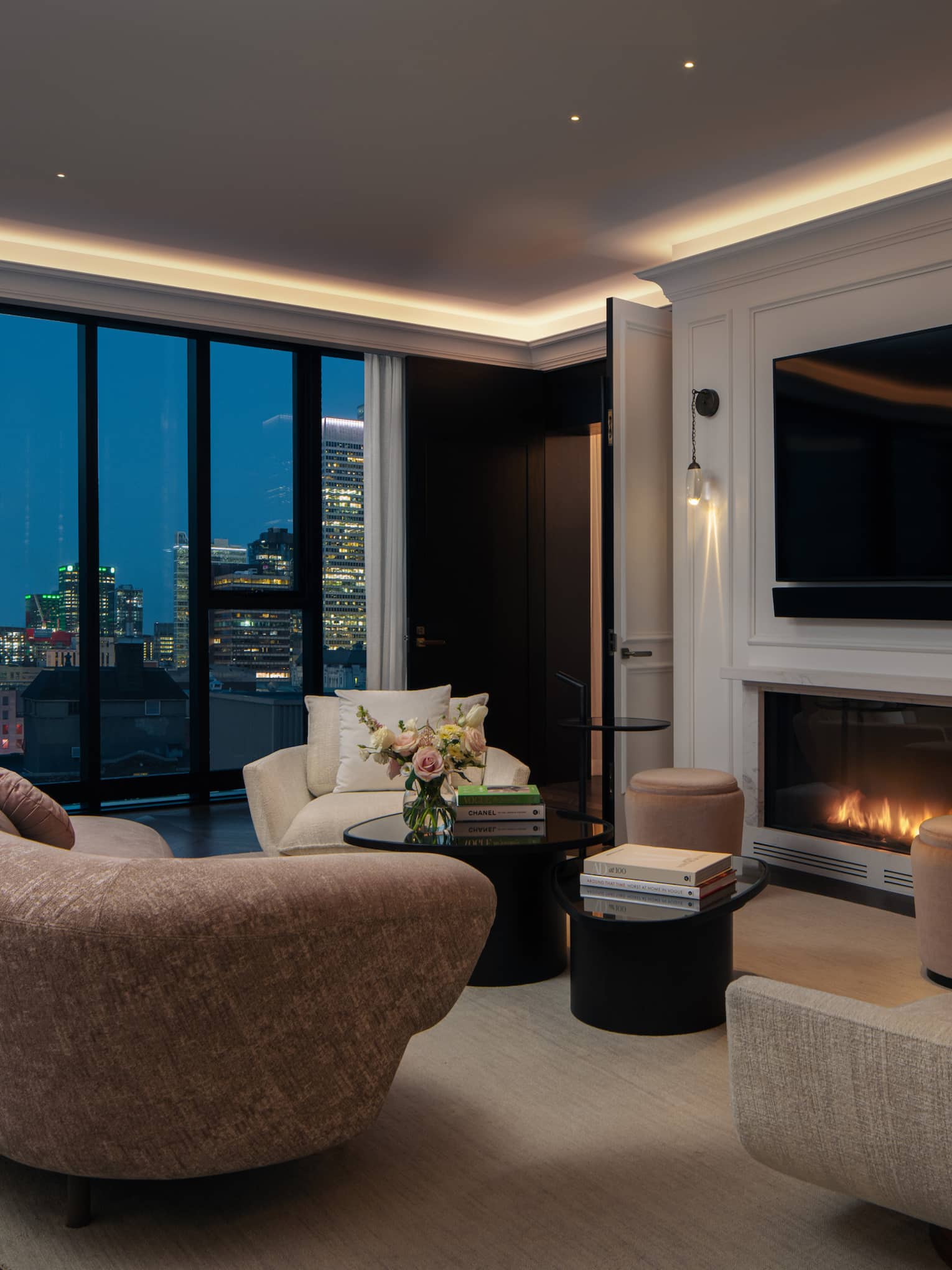 Living room with modern curved sofa and chairs, fireplace, TV and city evening view