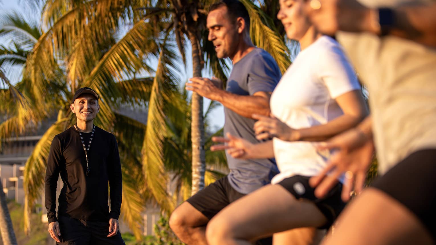 Fitness instructor leading an outdoor workout class with three guests.