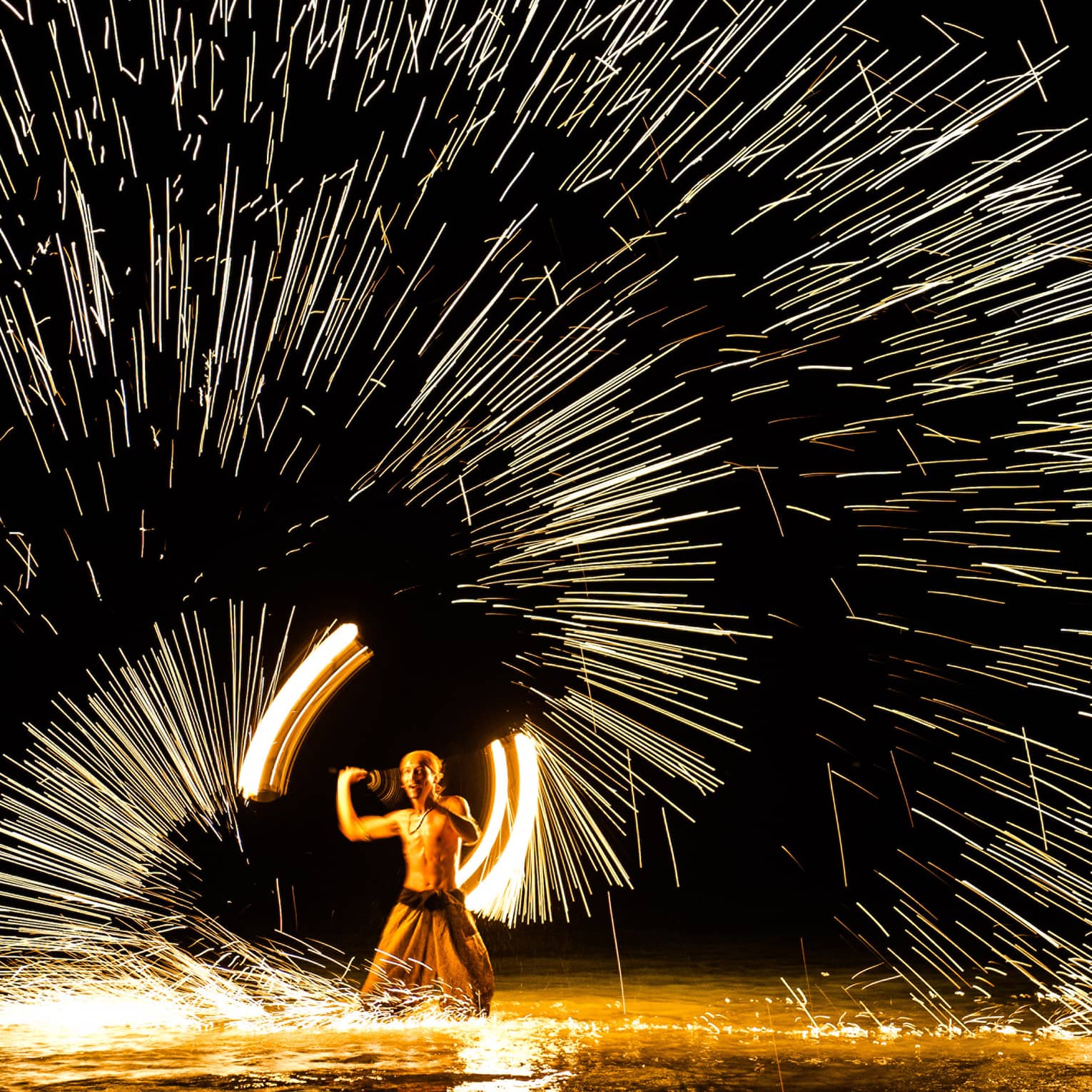 Streaks of light around man spinning fire 