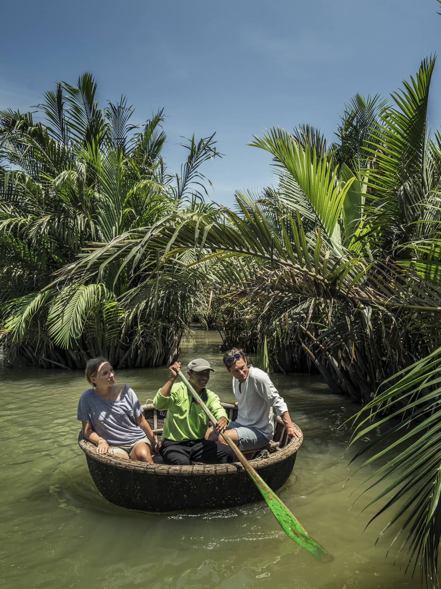 A couple and a guide in a Hoi An tour basket boat 