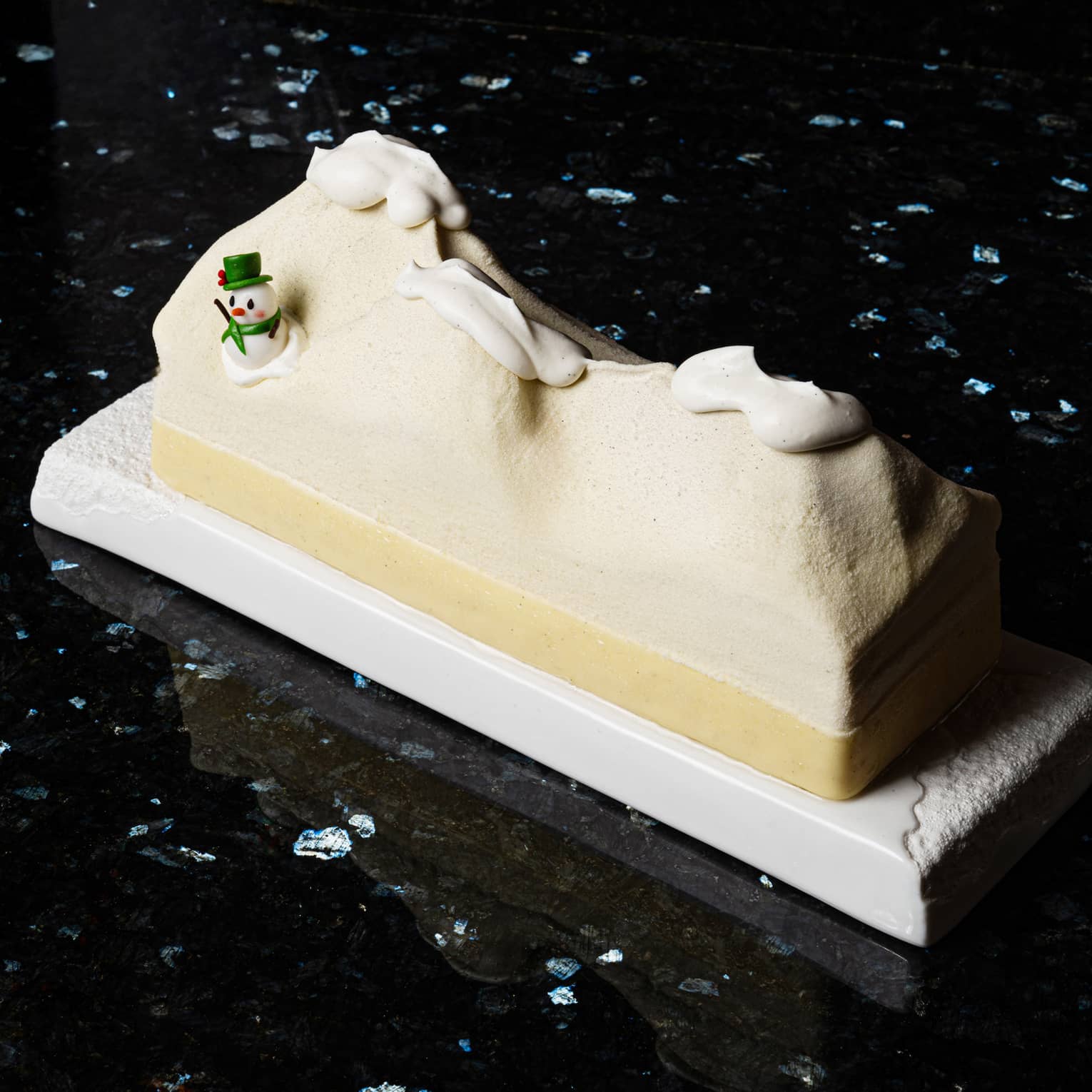 B�che de No�l shaped like desert dunes with snow on top and a snowman on one side