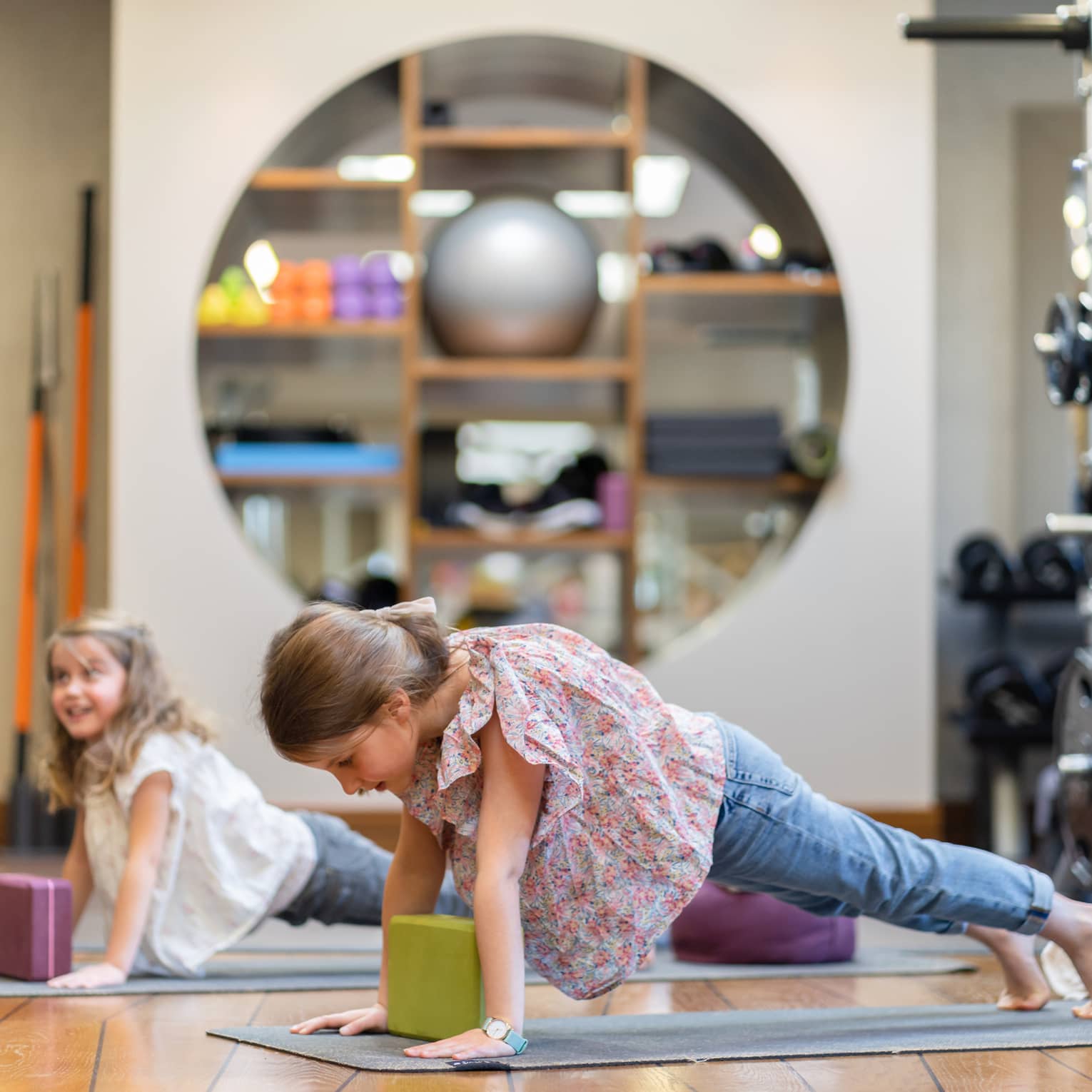 Two girls in downward dog yoga pose over yoga blocks and mats