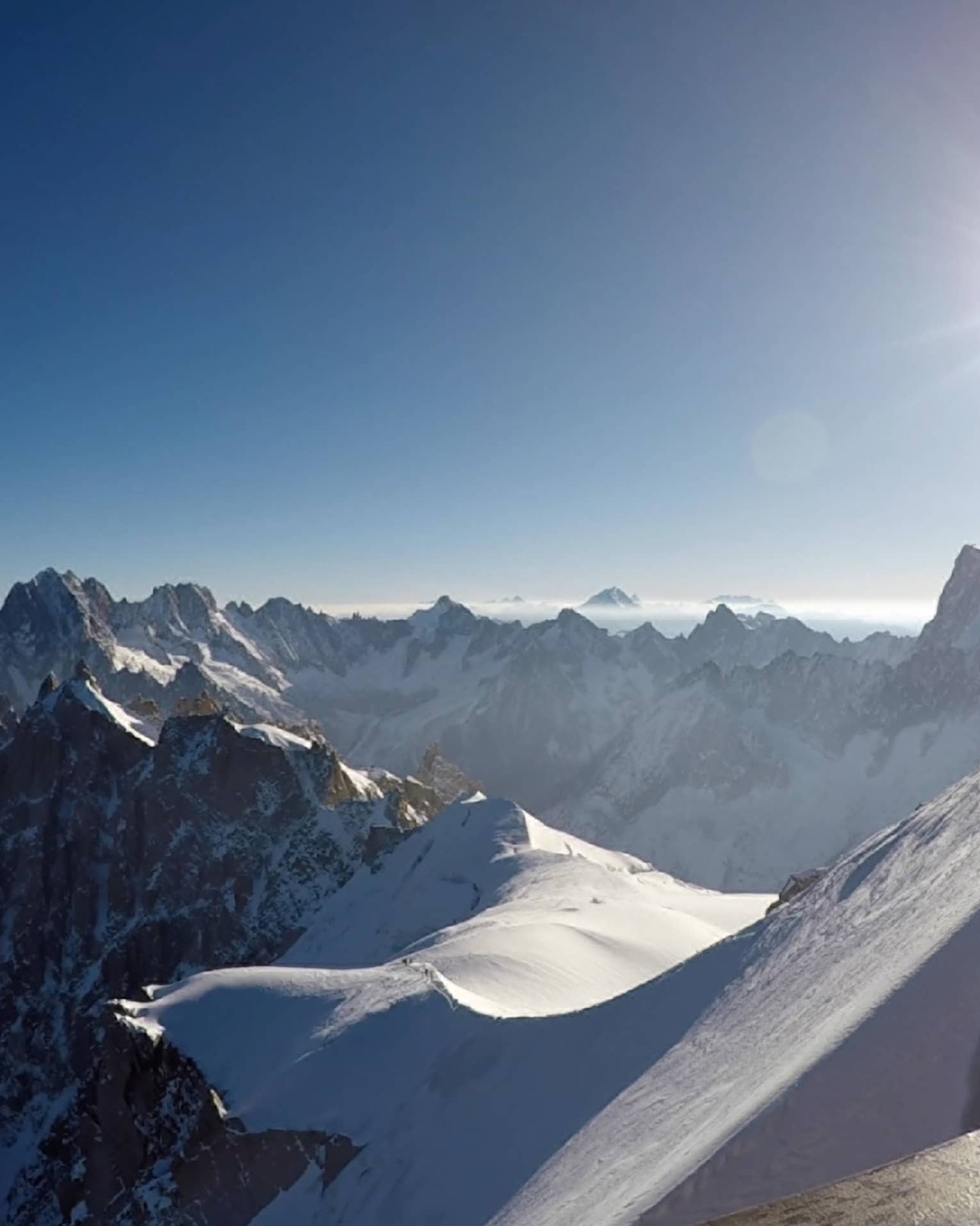 Snowy peaks of the French Alps with hazy sunshine in backdrop