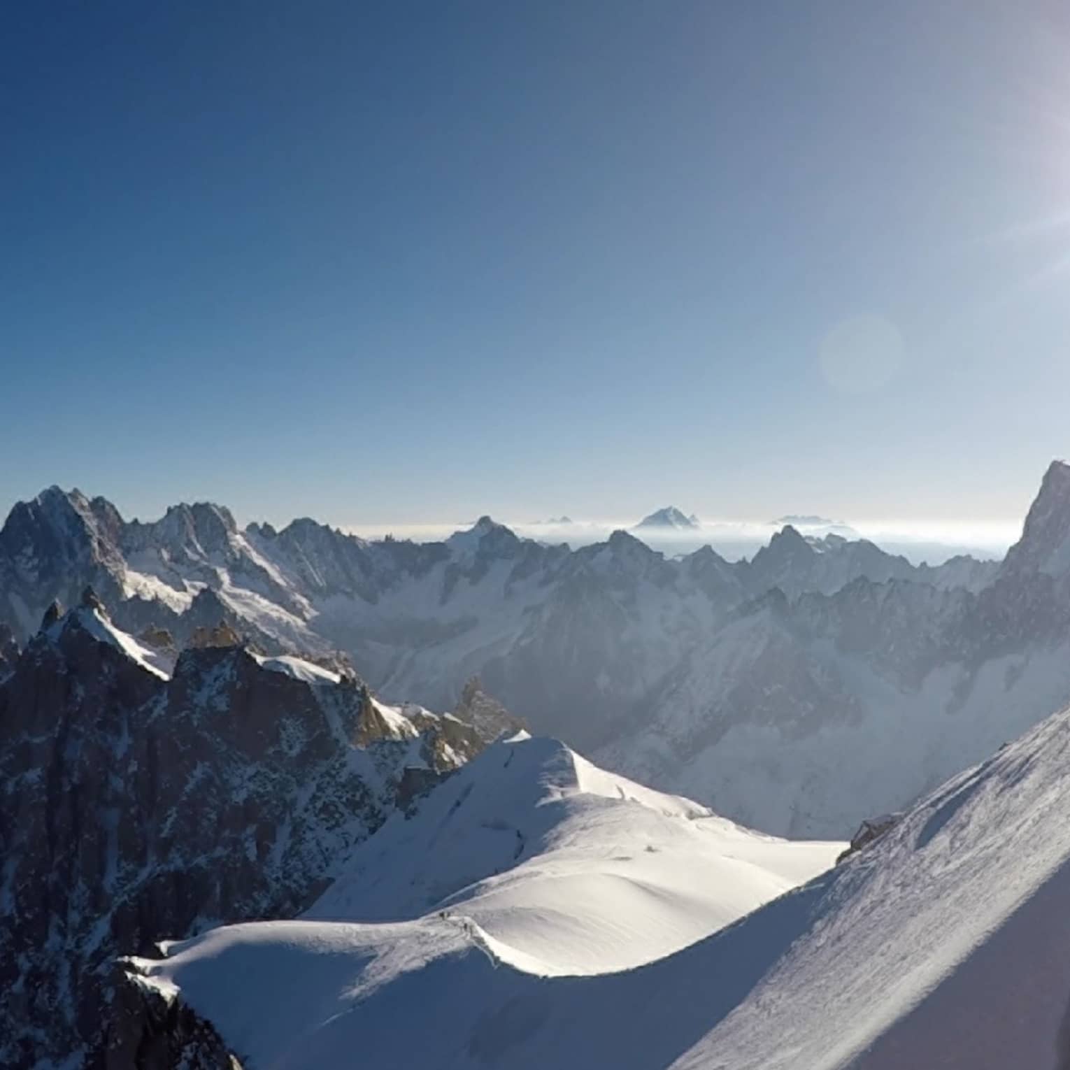 Snowy peaks of the French Alps with hazy sunshine in backdrop