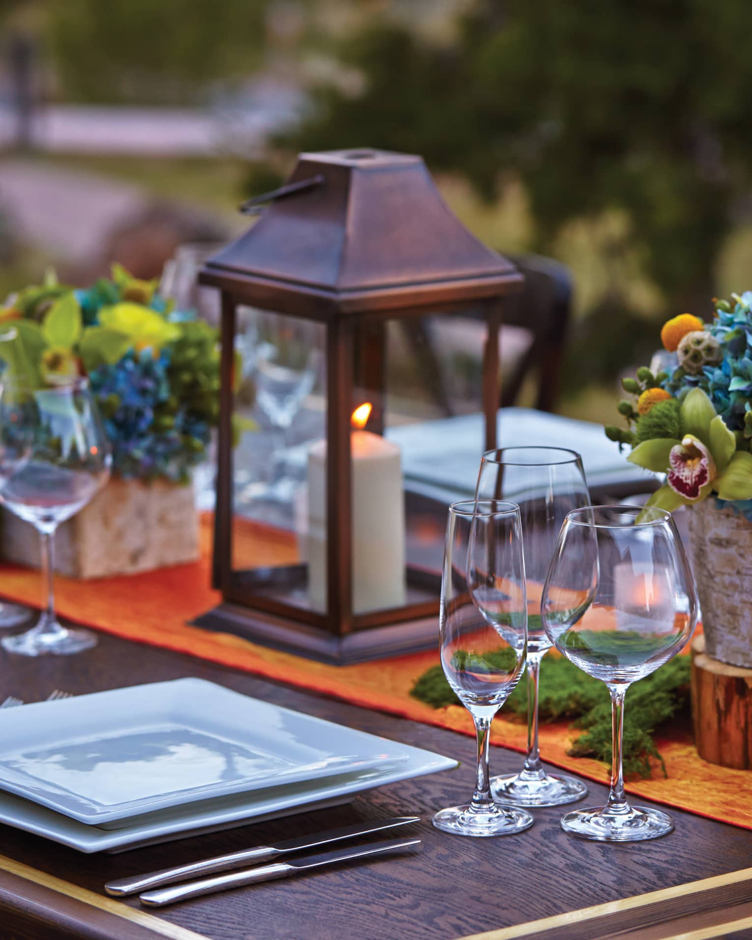 Close-up of lanterns, flowers on patio dining table at sunset