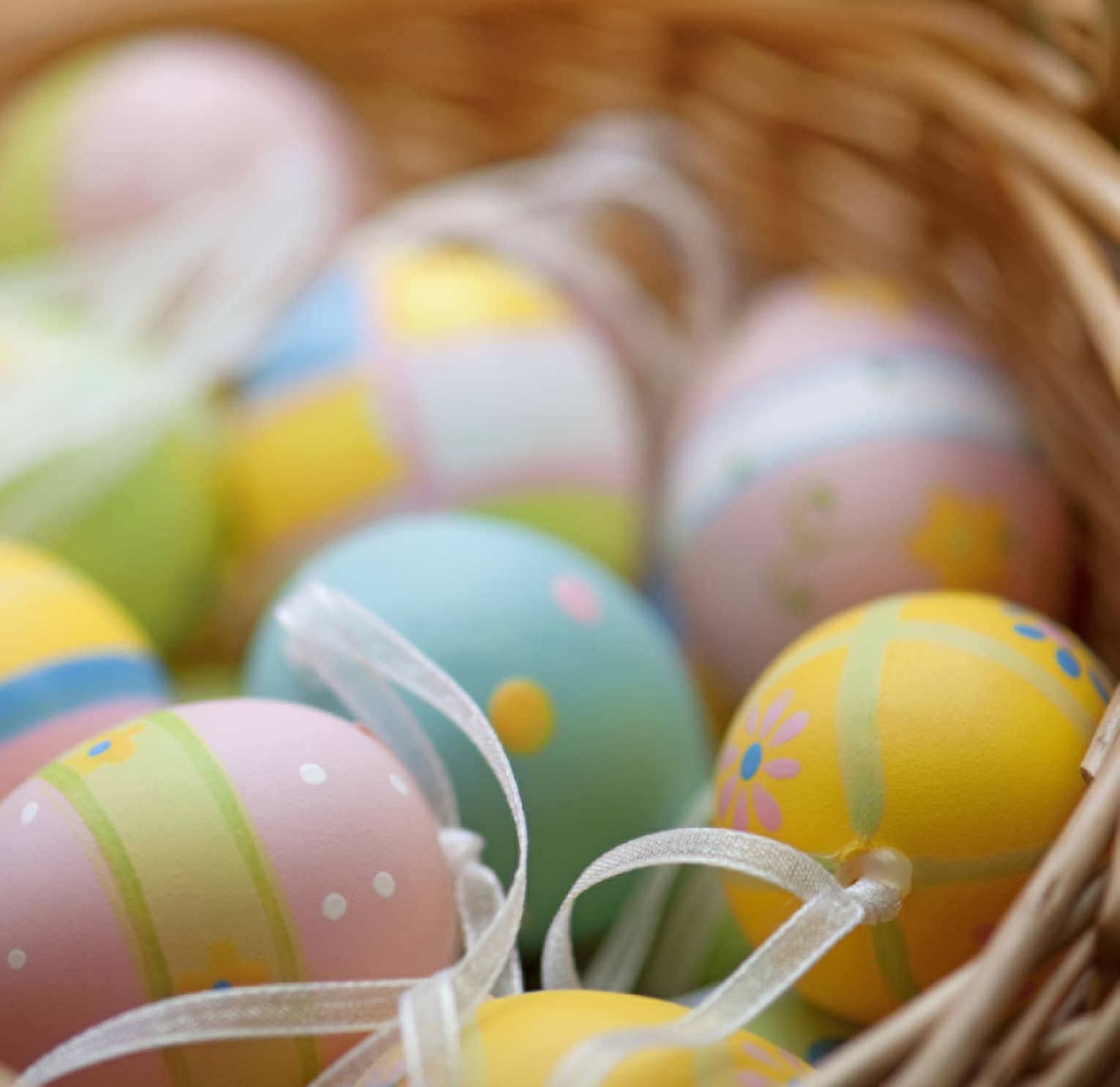 A basket of blue, pink, green and yellow colourful Easter eggs.