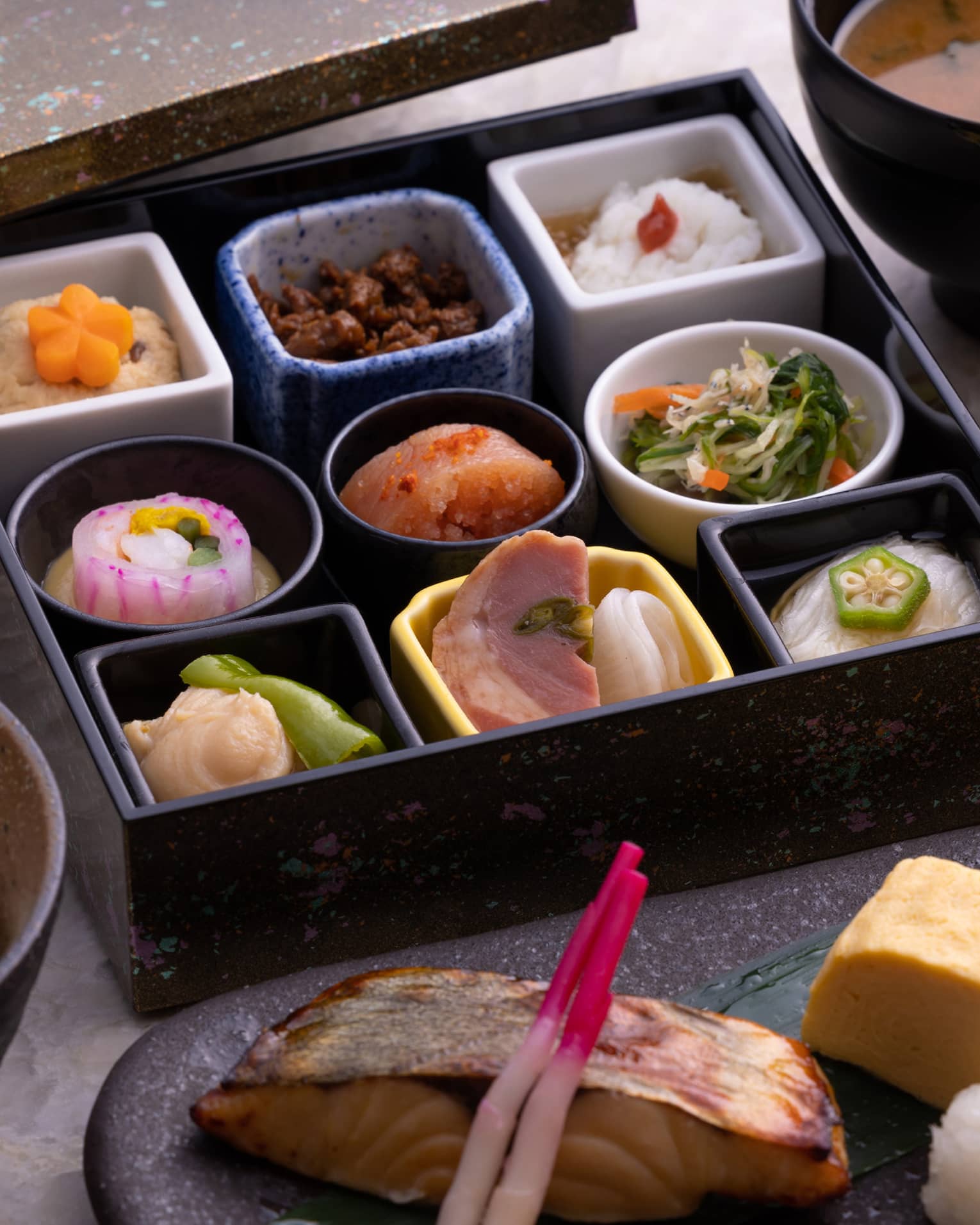 Traditional Japanese bento box breakfast with obanzai side dishes, tamagoyaki (Japanese rolled omelette), congee, steamed rice and miso soup