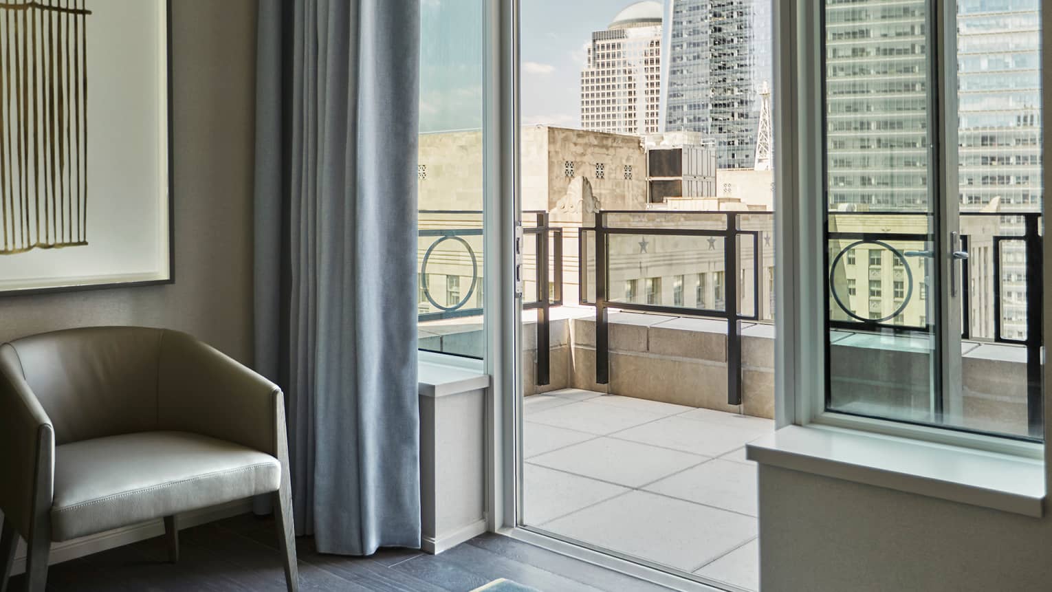 Tribeca Suite leather mid-century style chair by open door to tile balcony overlooking downtown New York