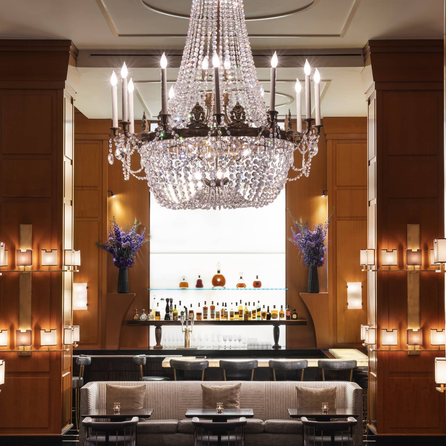 A bar area with a large chandelier and small lights on the walls.