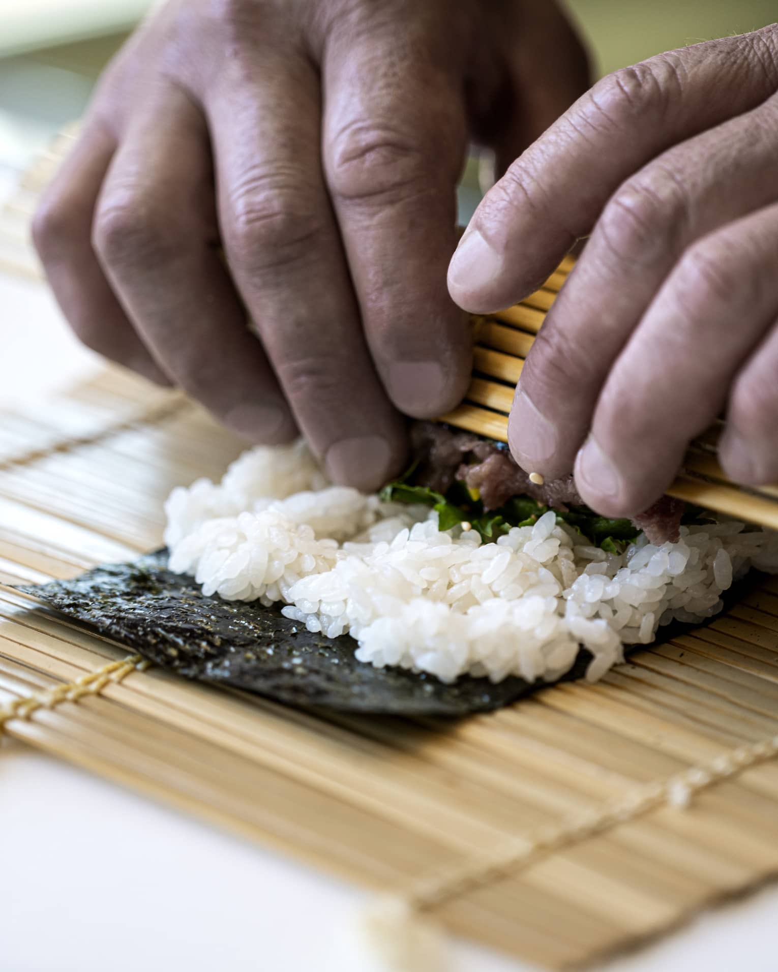 A four seasons chef rolls sushi with a bamboo mat 