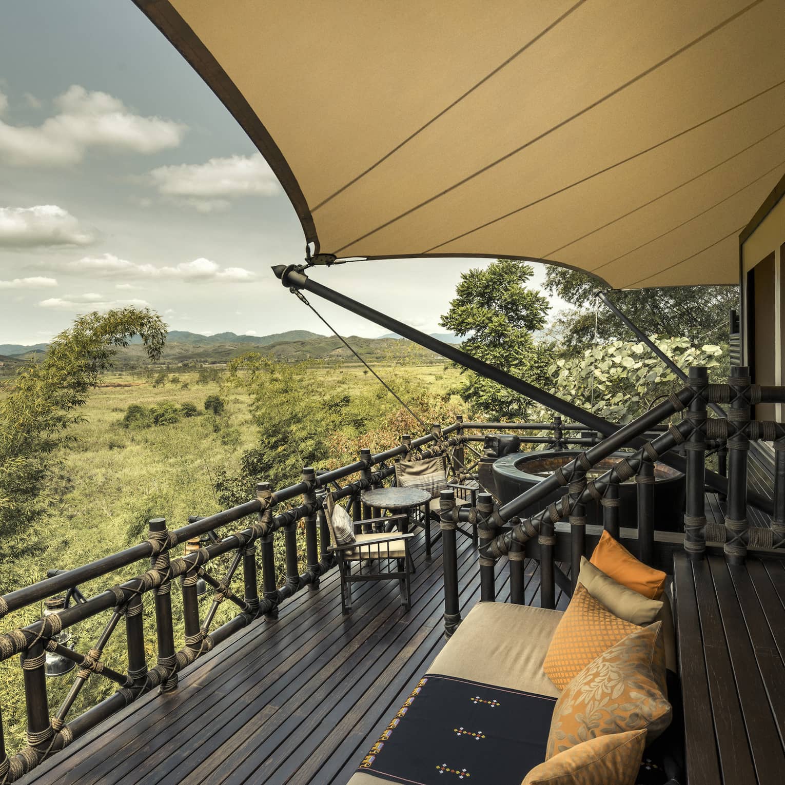 View from balcony of luxury tent: breathtaking scenery, lush greenery, and a clear blue sky.