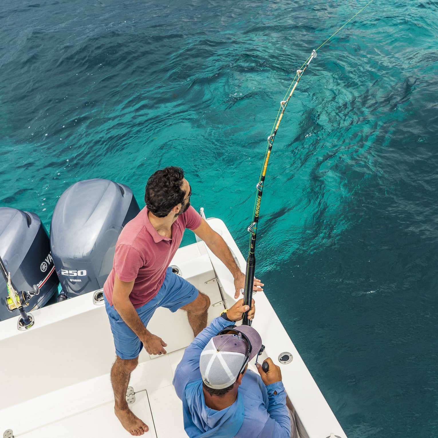 Aerial view of two men fishing off white boat with fishing rods