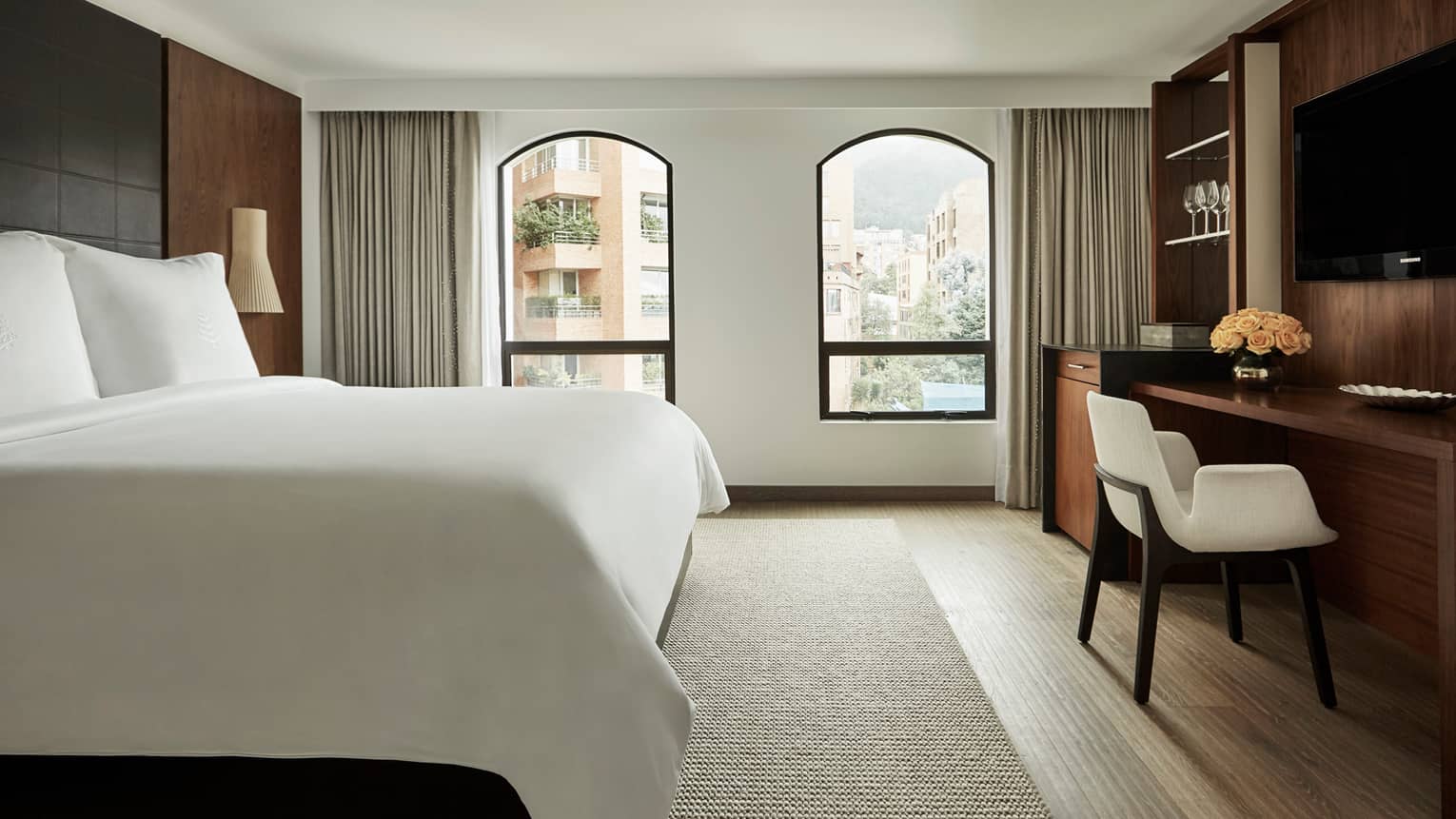 Superior Room bed, two windows with sunny city view, flat-screen TV over wood desk with white chair