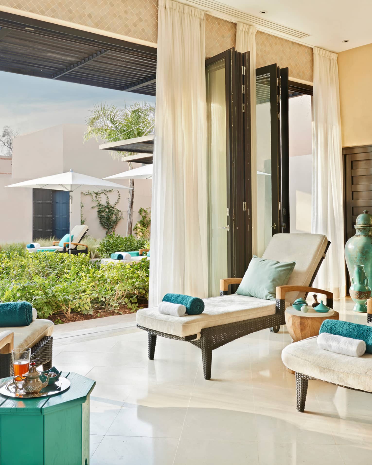 Lounge chairs with rolled towels in large open-air sunny spa patio