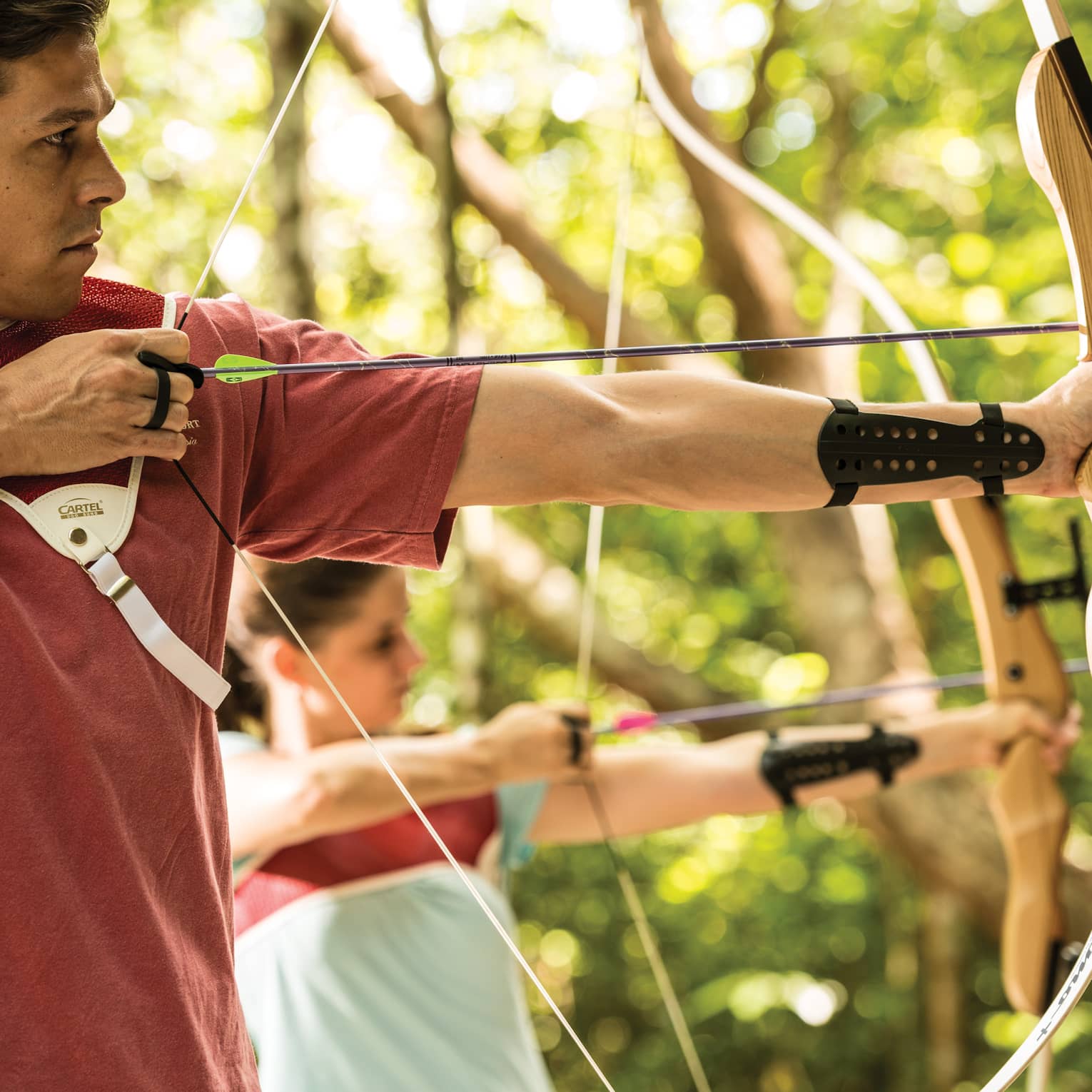 Man and woman hold bow and arrow, prepares to shoot