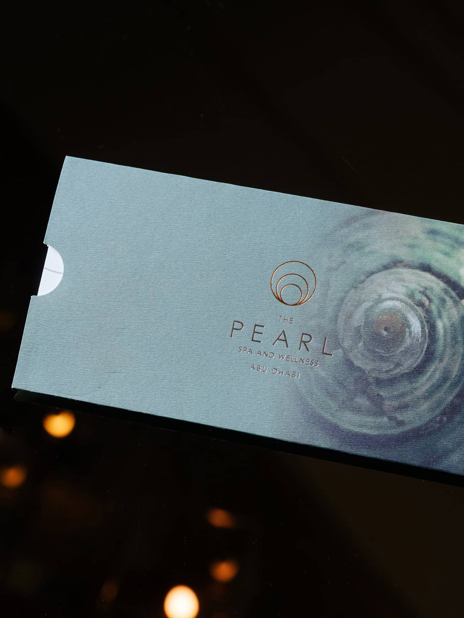 Light-blue metallic gift card for The Pearl Spa set on a black backdrop