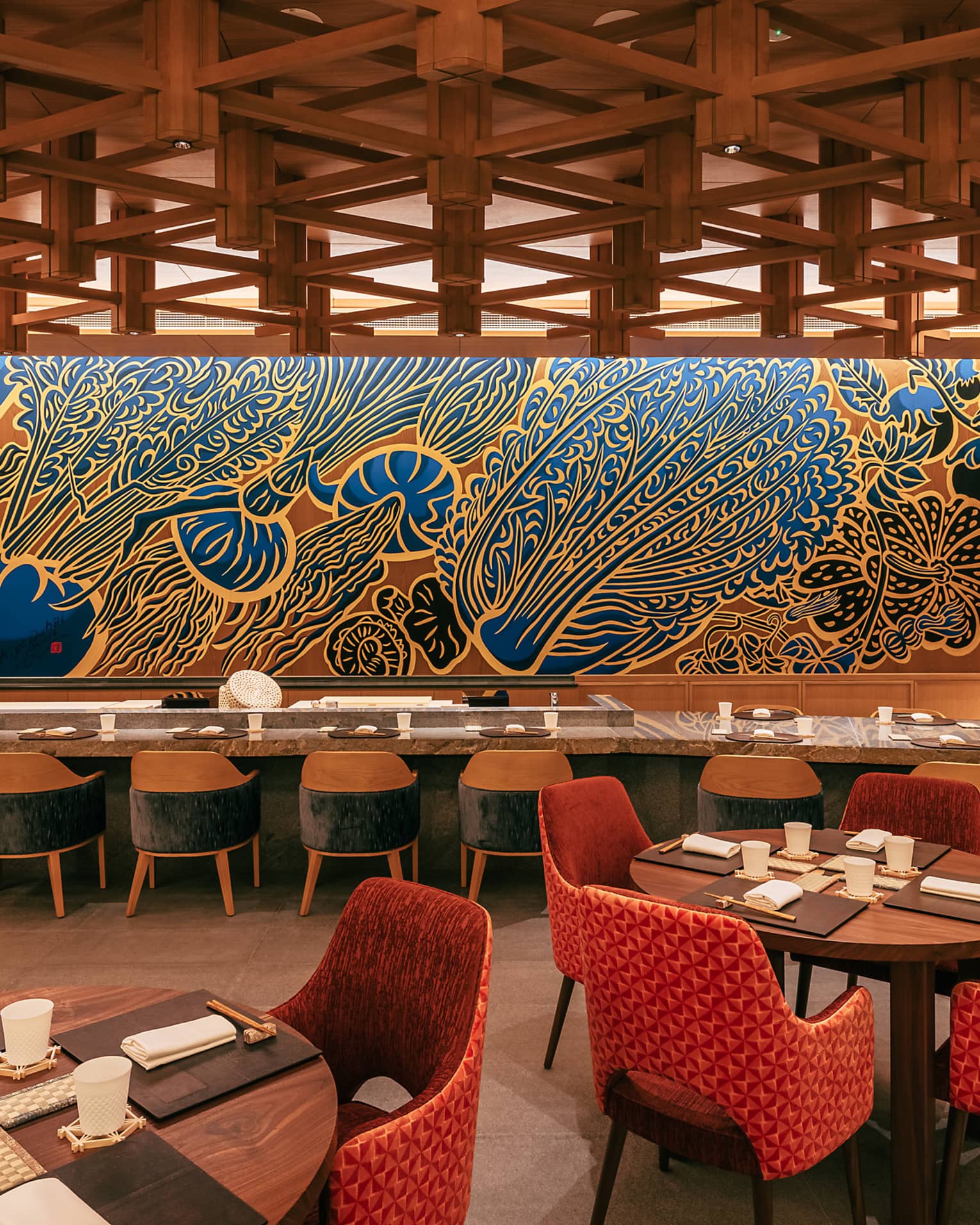 Restaurant dining room with a long rectangular communal table and various round tables set for four