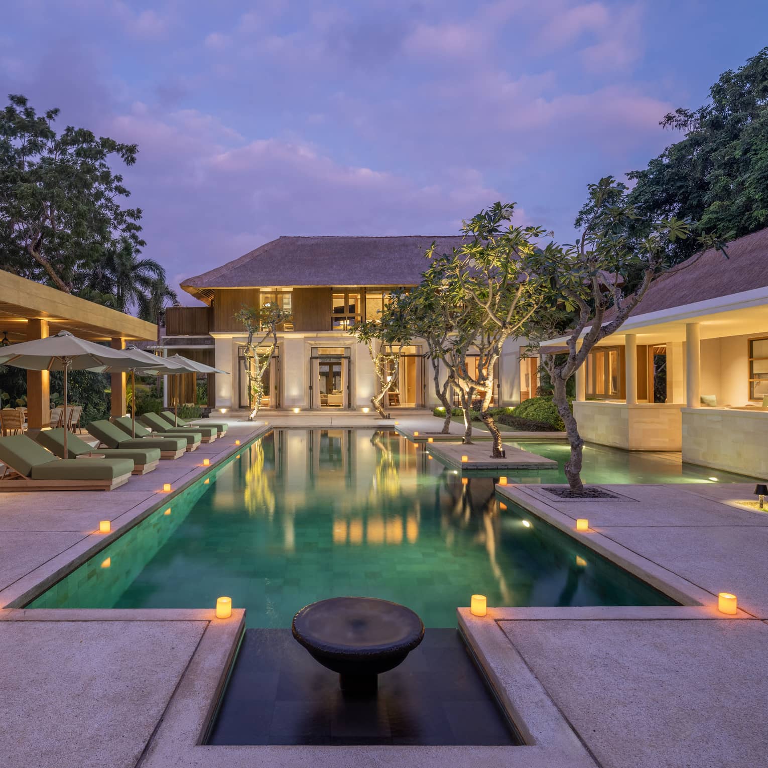 Private residence swimming pool and pool terrace illuminated at dusk, at Four Seasons Resort Bali at Jimbaran Bay