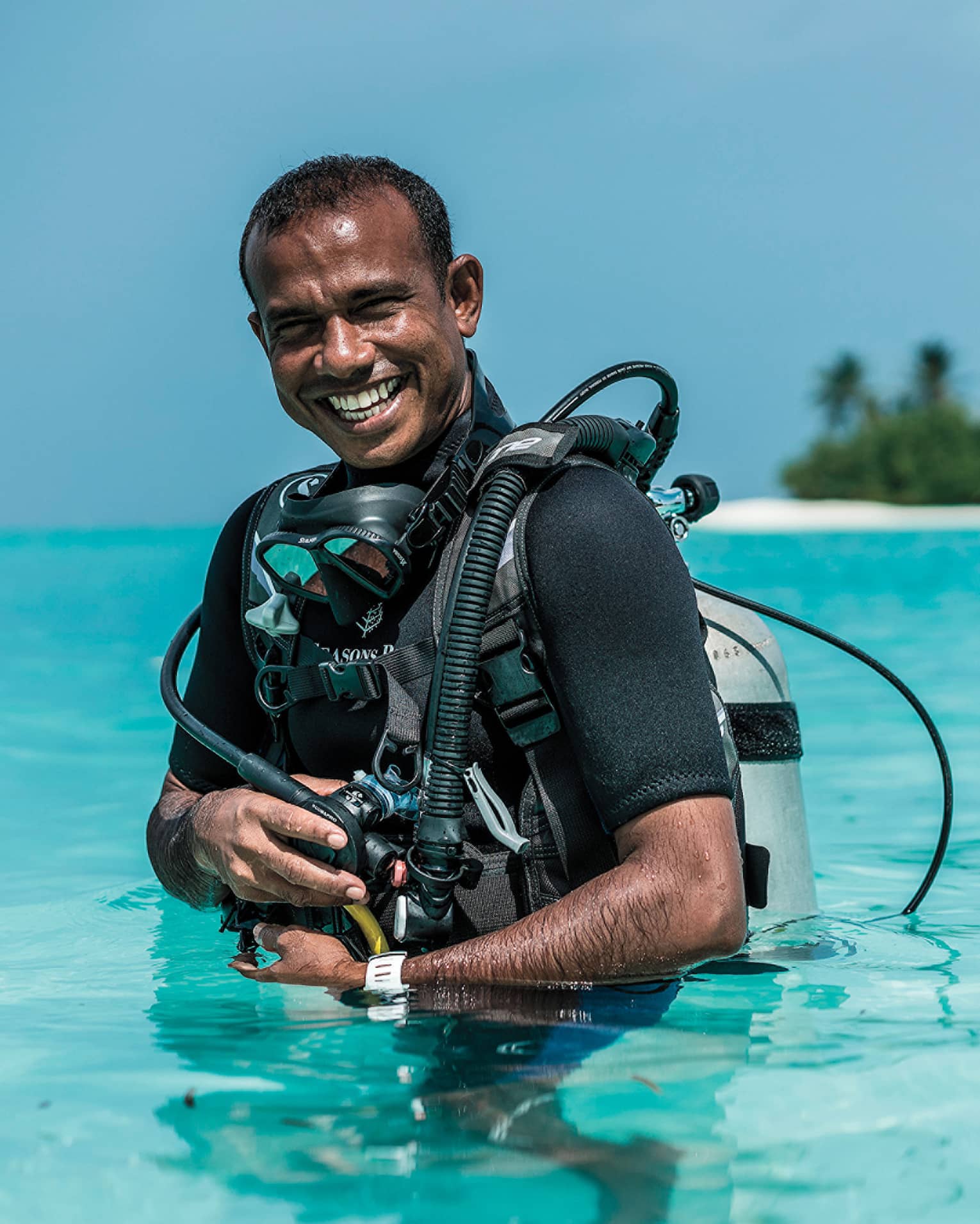 Smiling Dive Manager Ibrahim Nazeer with scuba gear in the crystal clear waters of the lagoon
