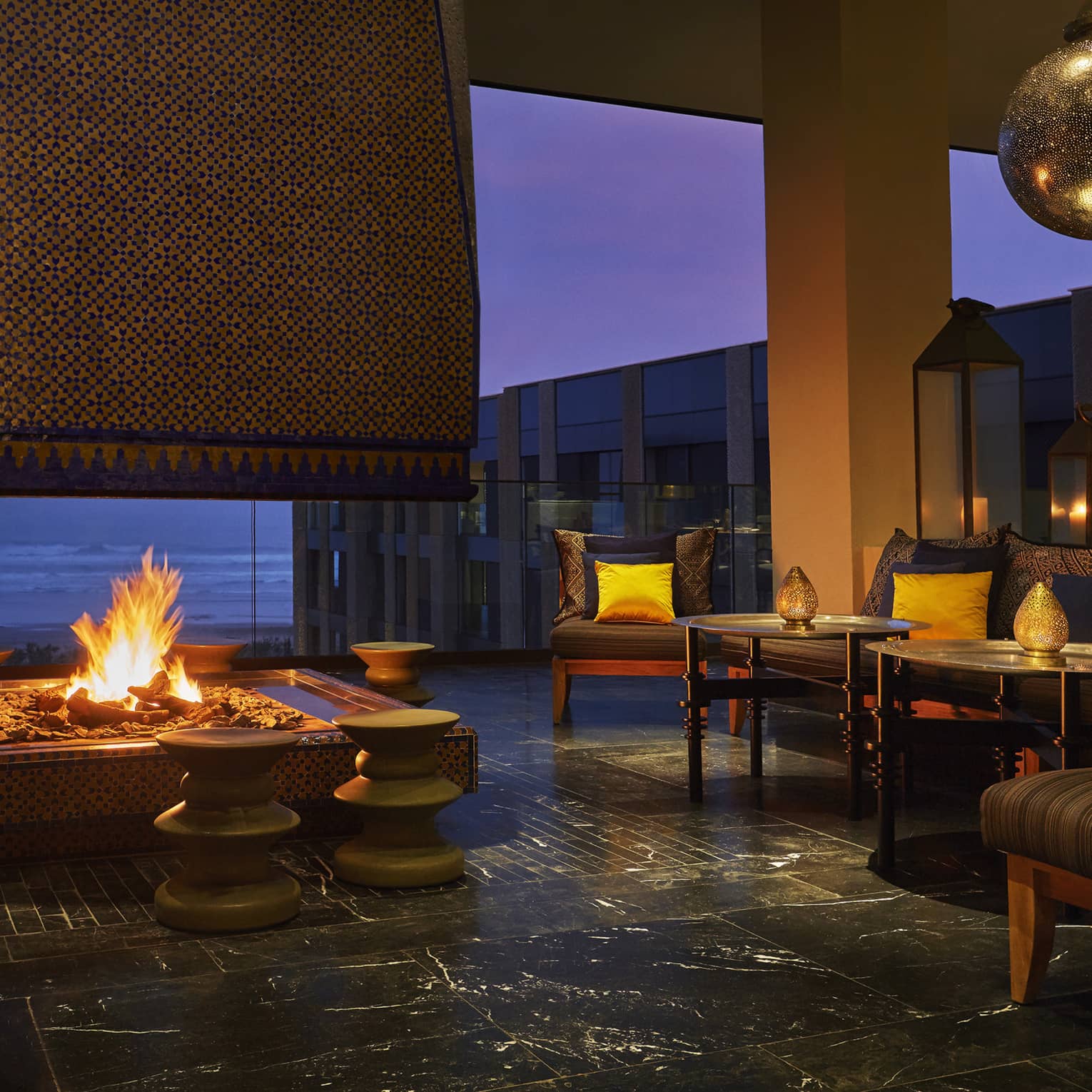 Patios sofas, beaches around large outdoor fireplace on Mint terrace at night