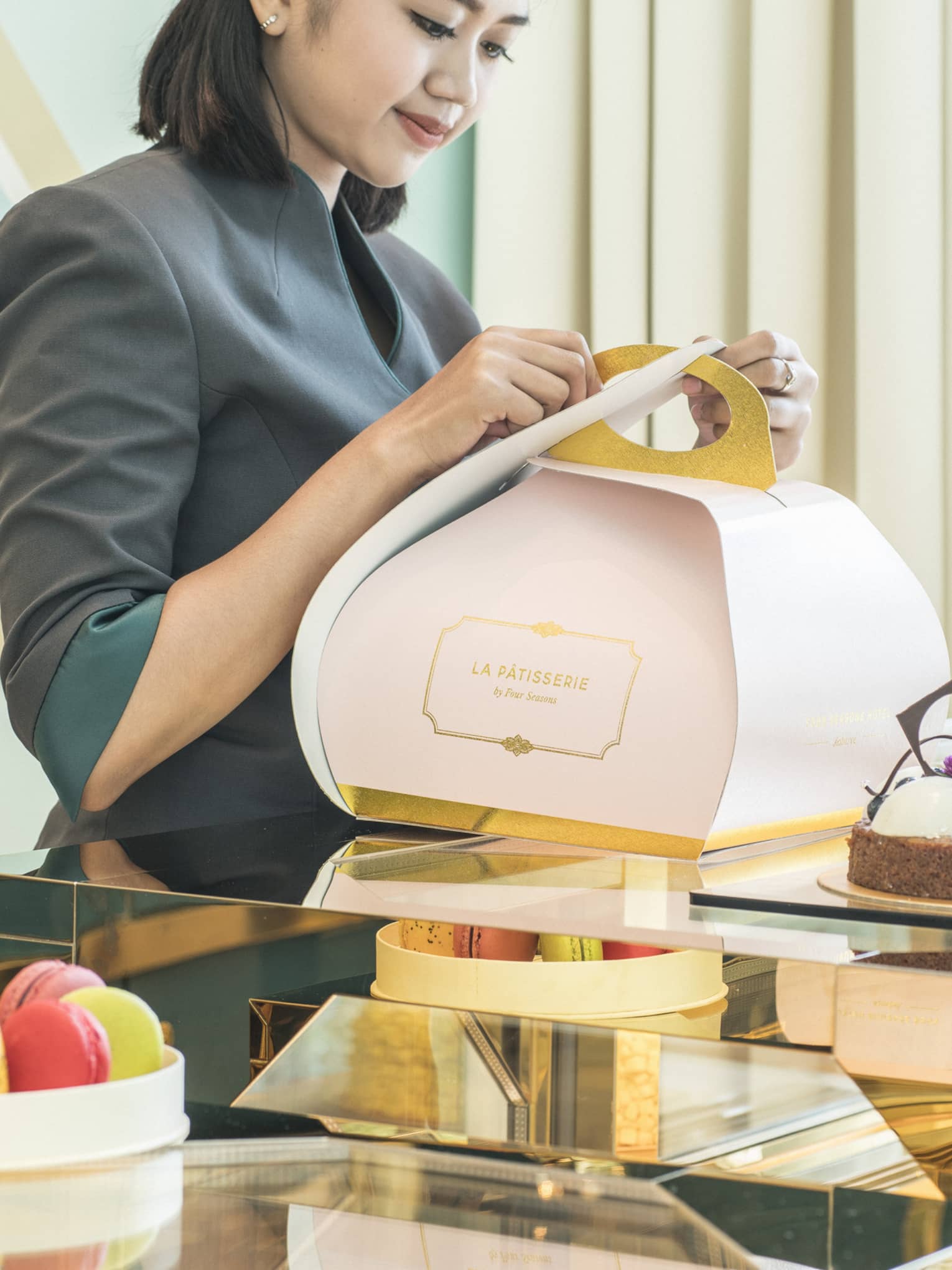 Woman wrapping a pastry in a stylish light pink box for take away